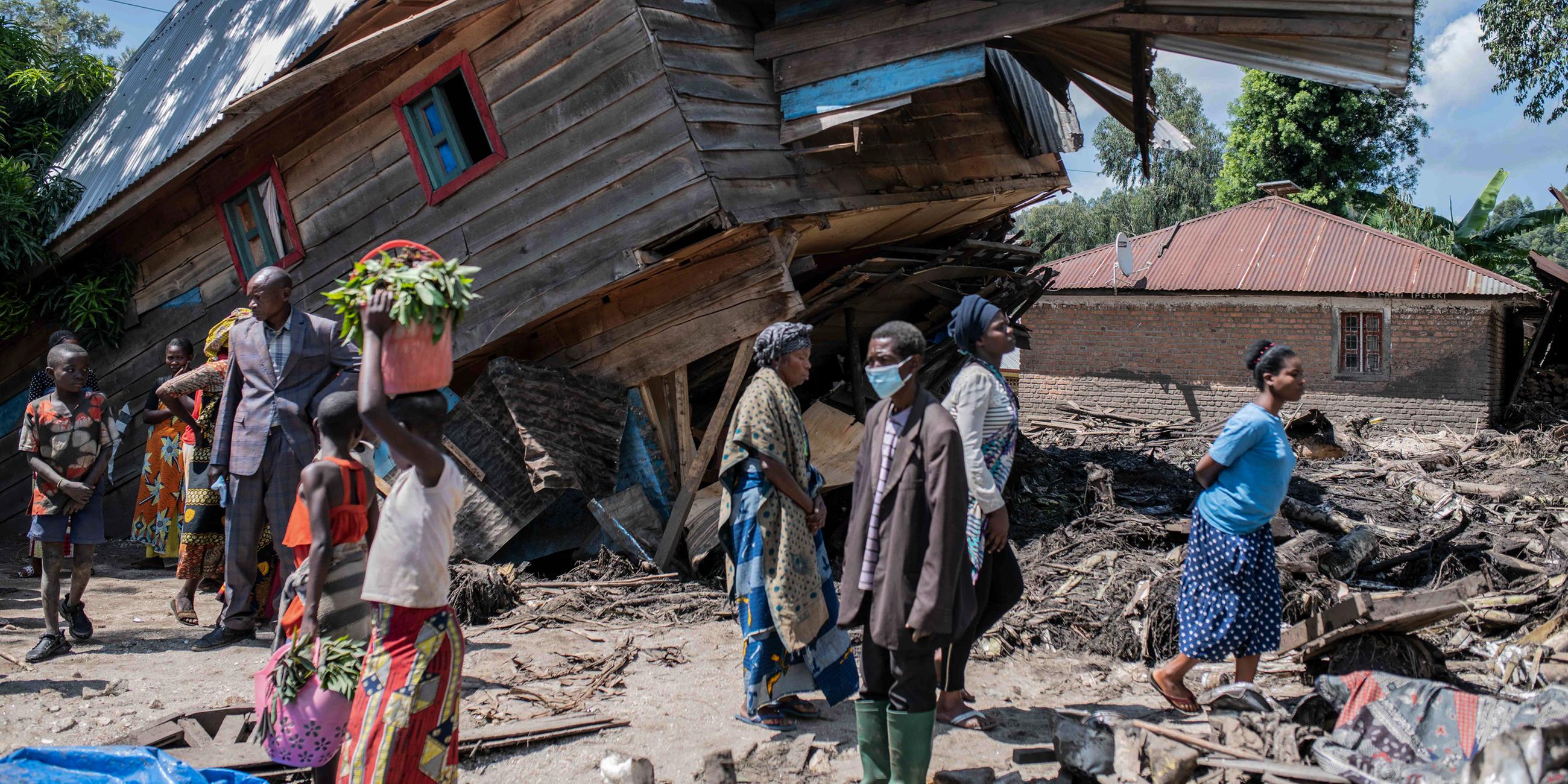 Menschen neben einem, von den Überschwemmungen zerstörten, Haus im Dorf Nyamukubi in der Provinz Süd-Kivu im Kongo