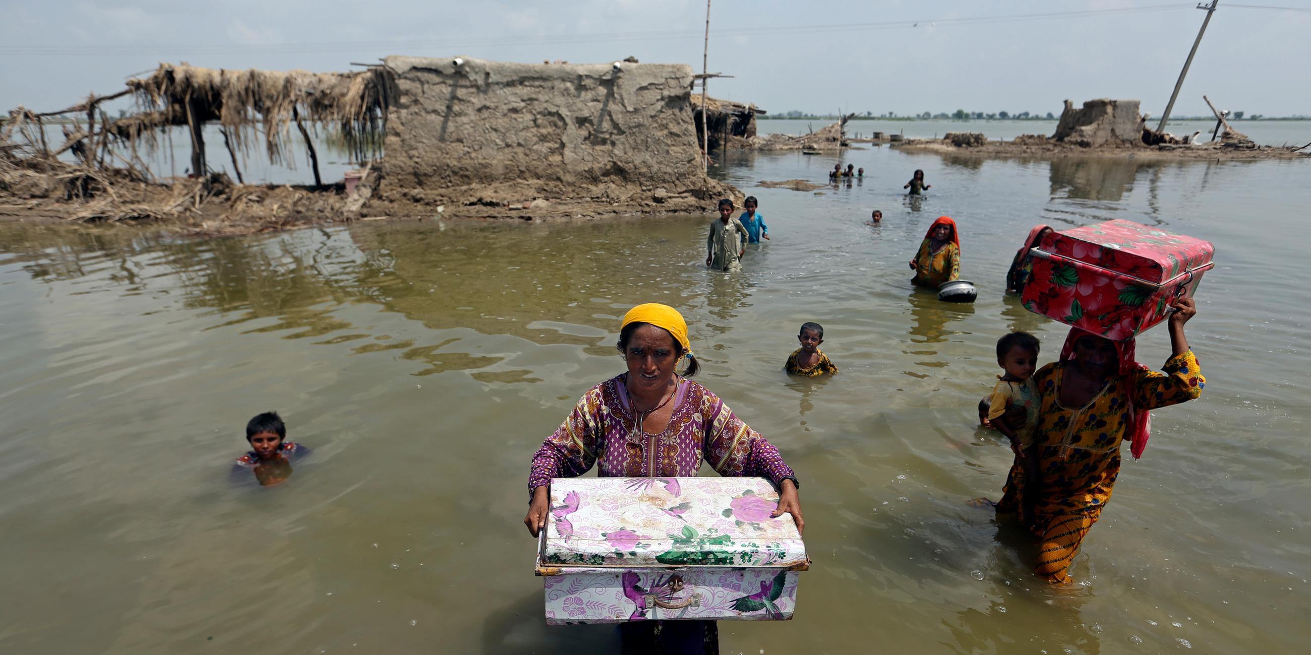 Frauen tragen Besitz aus überschwemmten Haus