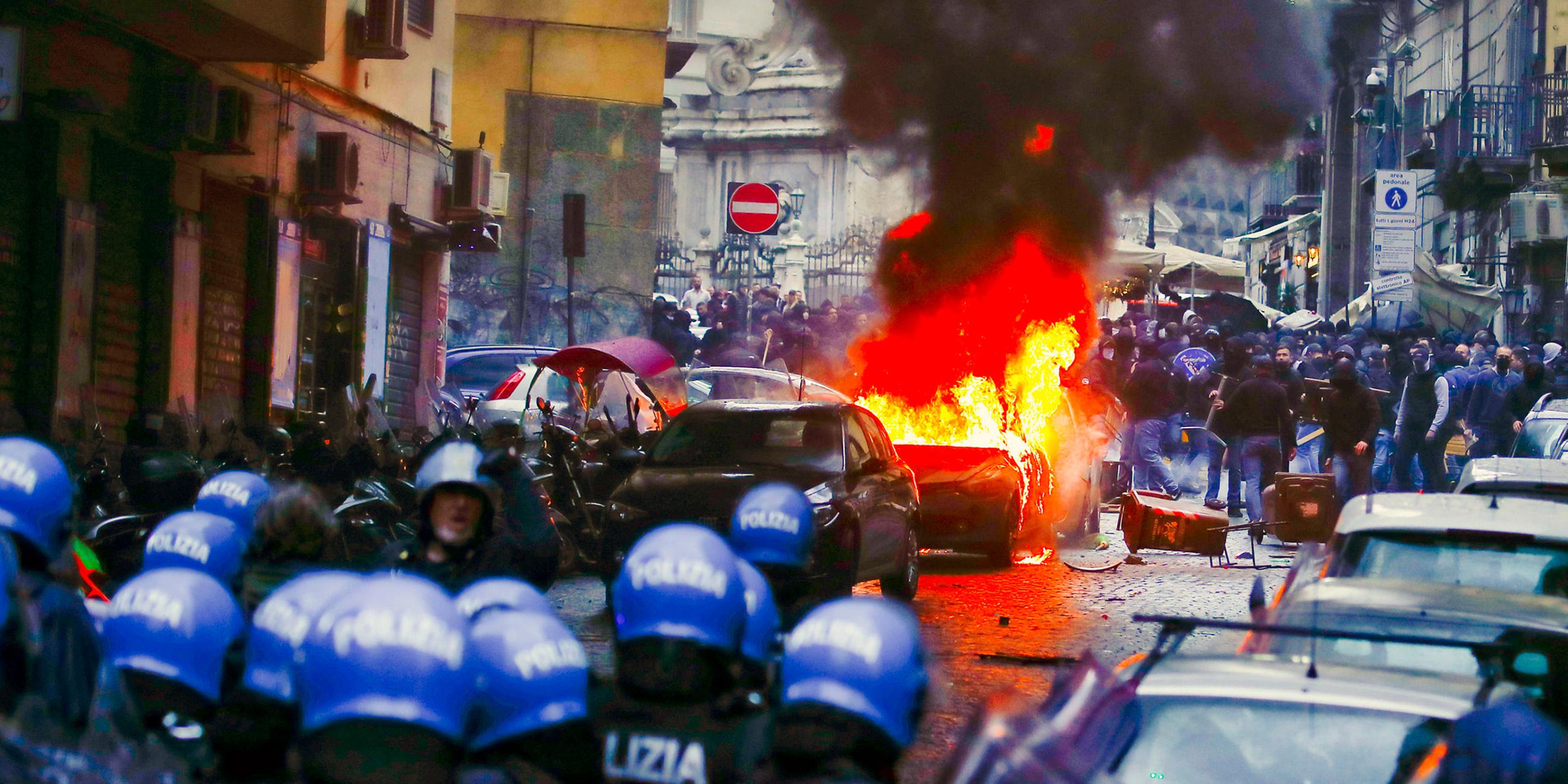 Ein Polizeiauto wird bei Zusammenstößen mit Anhängern von Eintracht Frankfurt in Brand gesetzt in Napoli am 15.03.2023. 