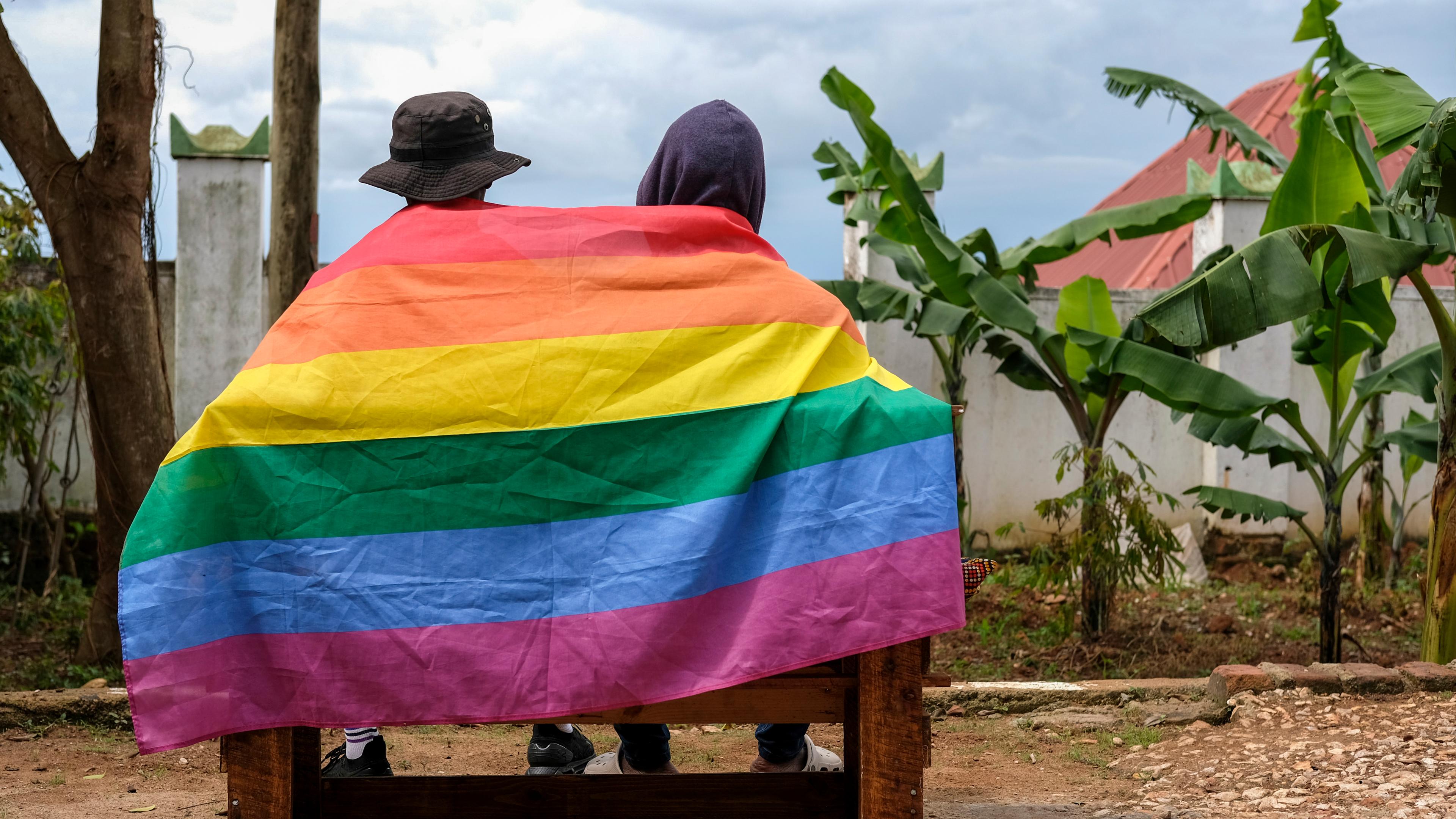 Ein schwules ugandisches Paar bedeckt sich mit einer Pride Flagge, während es für ein Foto in Uganda posiert. 
