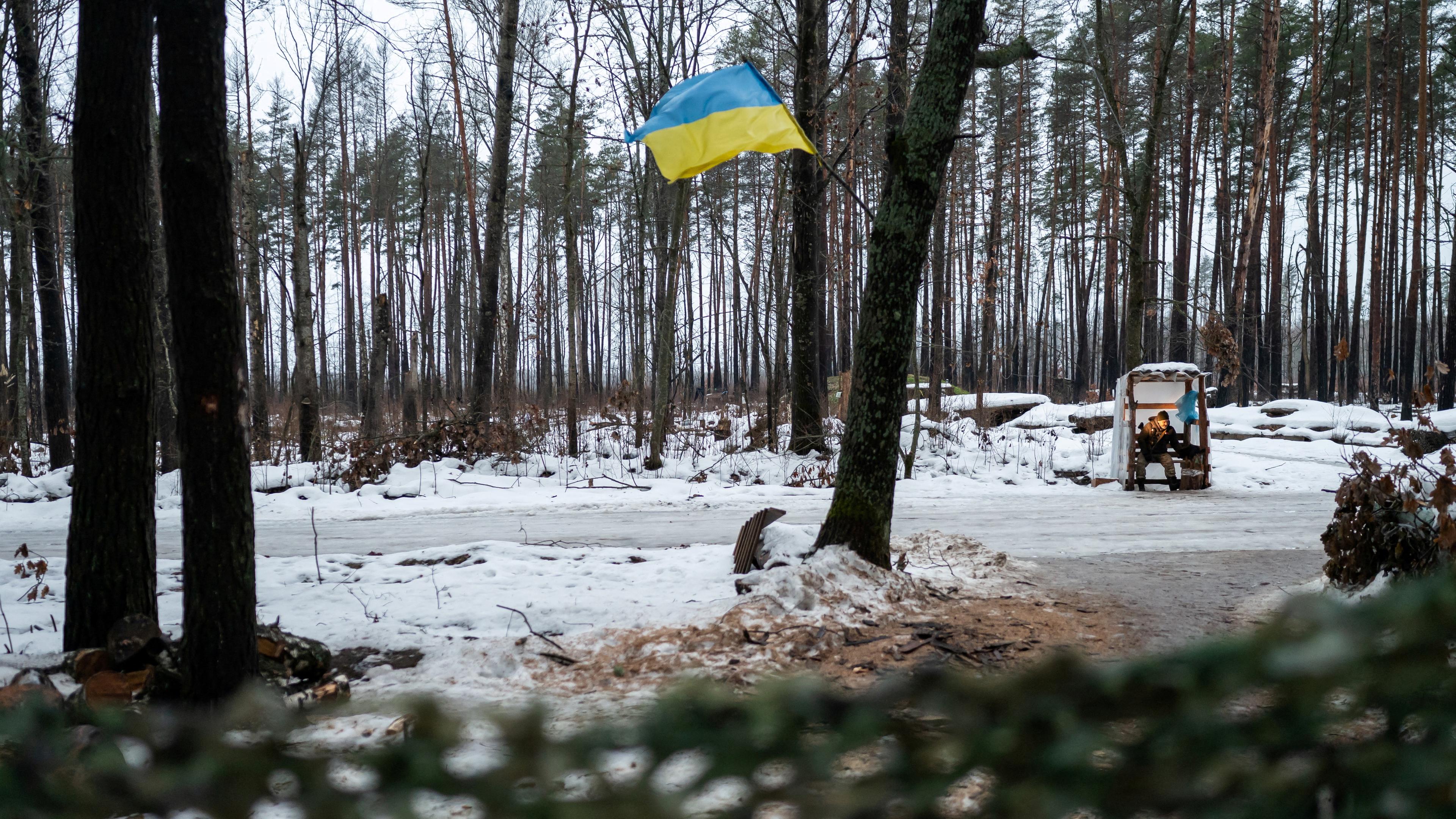 Eine ukrainische Flagge in einer verschneiten Landschaft in der Ukraine, nah der Belarussischen Grenze