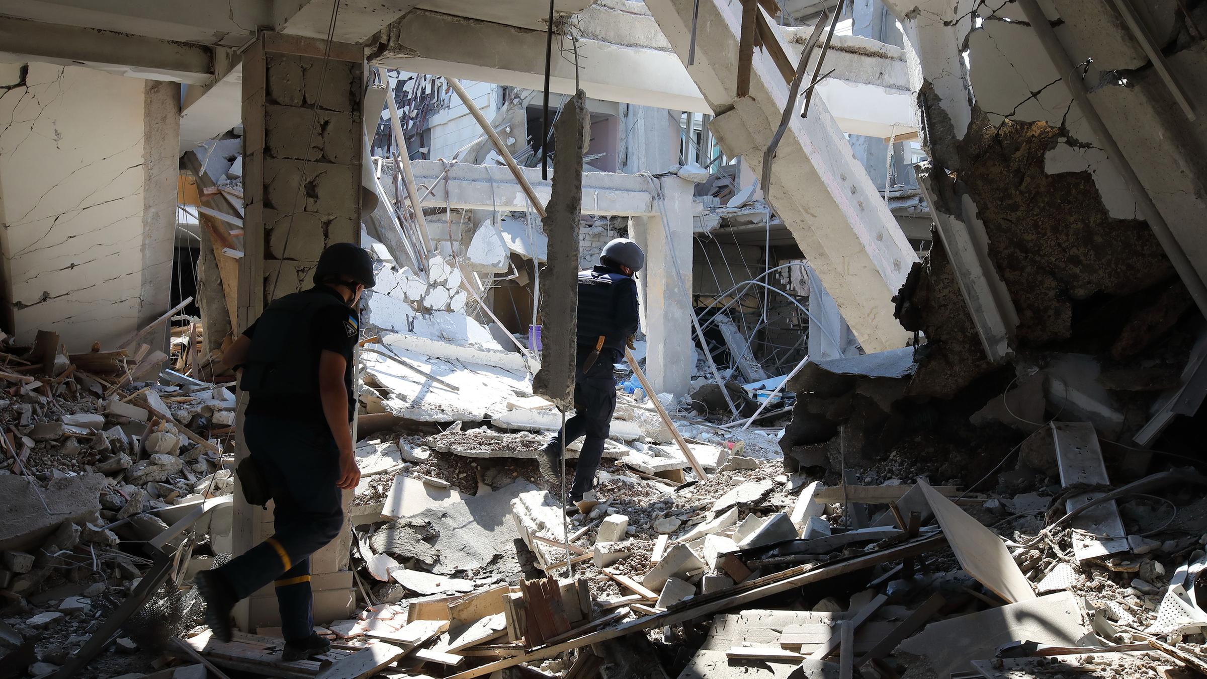 Rescuers walk through a destroyed building of the National Pedagogical University after being hit by Russian rocket fire.  f