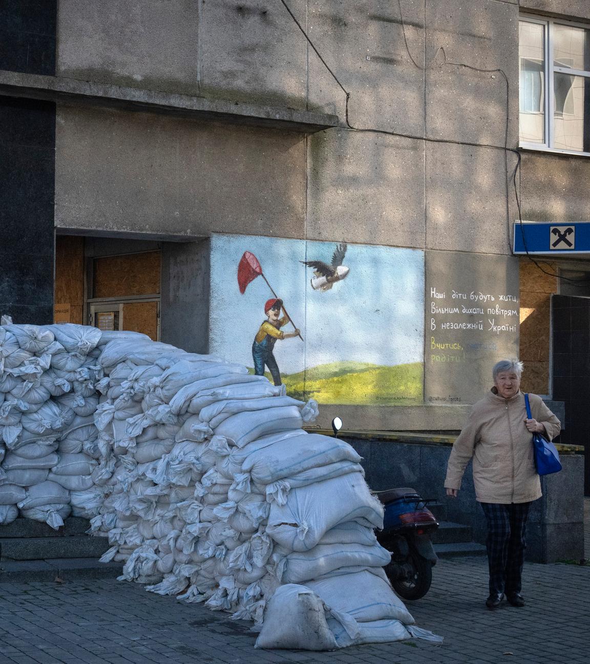 Archiv: Eine Anwohnerin geht an Sandsäcken vorbei, die das Postamt der Stadt schützen. (10.11.2023)