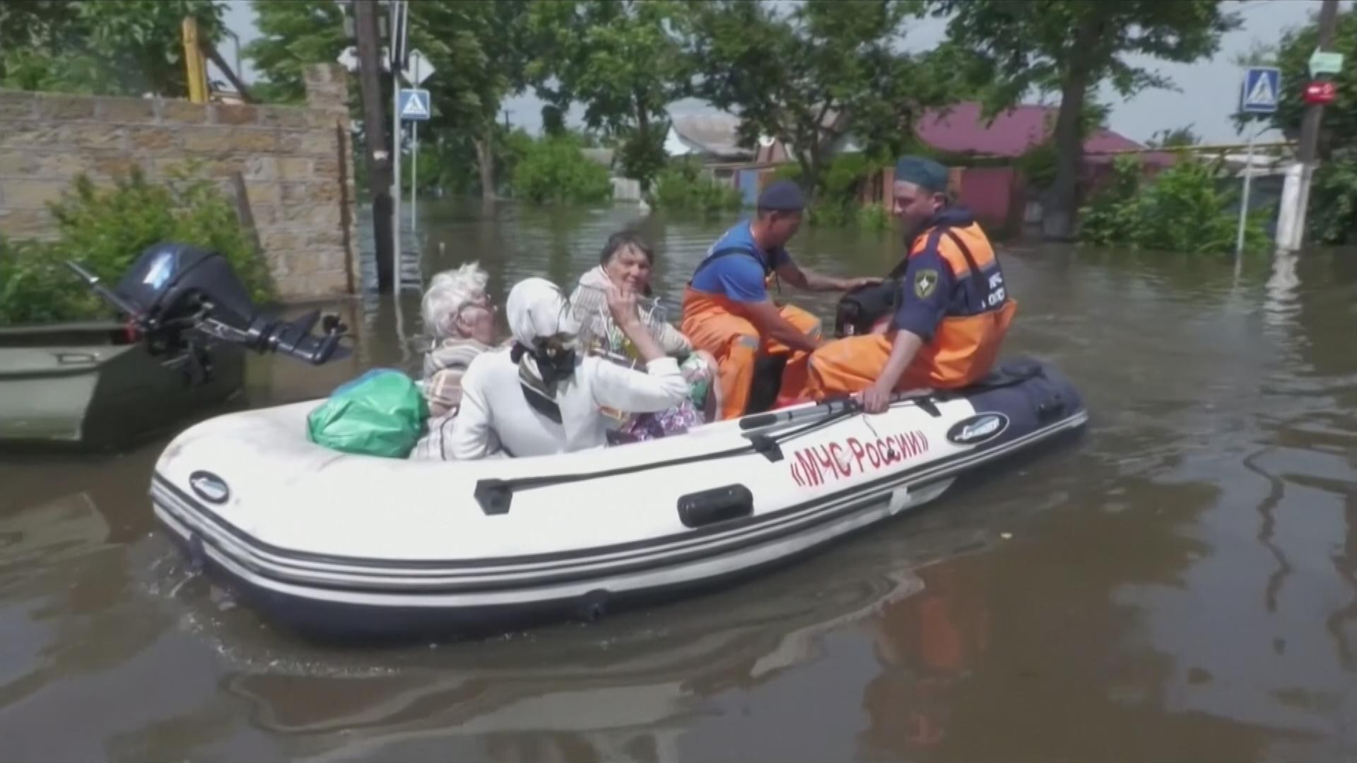 Menschen werden von Einsatzkräften mit einem Rettungsbot aus einem Flutgebiet evakuiert.