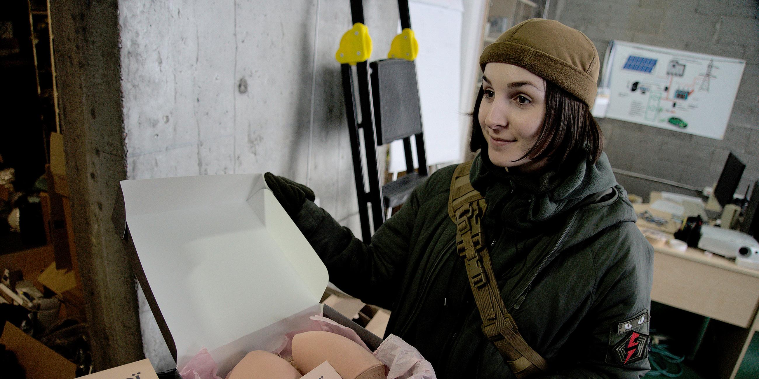 Anastasia Mochina zeigt ein Paket mit Ausrüstung für ukrainische Soldatinnen.