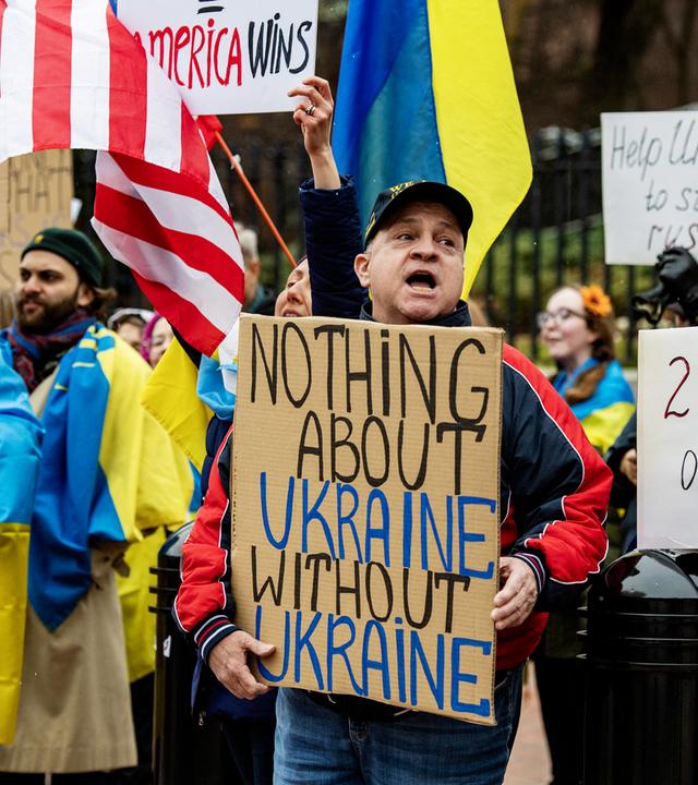 Demonstranten mit gelb-blauen ukrainischen Flaggen halten Plakate hoch, auf denen sie einen Mitbestimmung der Ukraine bei Friedensverhandlungen fordern.