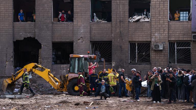 15.05.2026, Ukraine, Kiew: Menschen schauen durch die Fenster eines beschädigten Gebäudes nach einem russischen Angriff auf ein Wohnviertel.