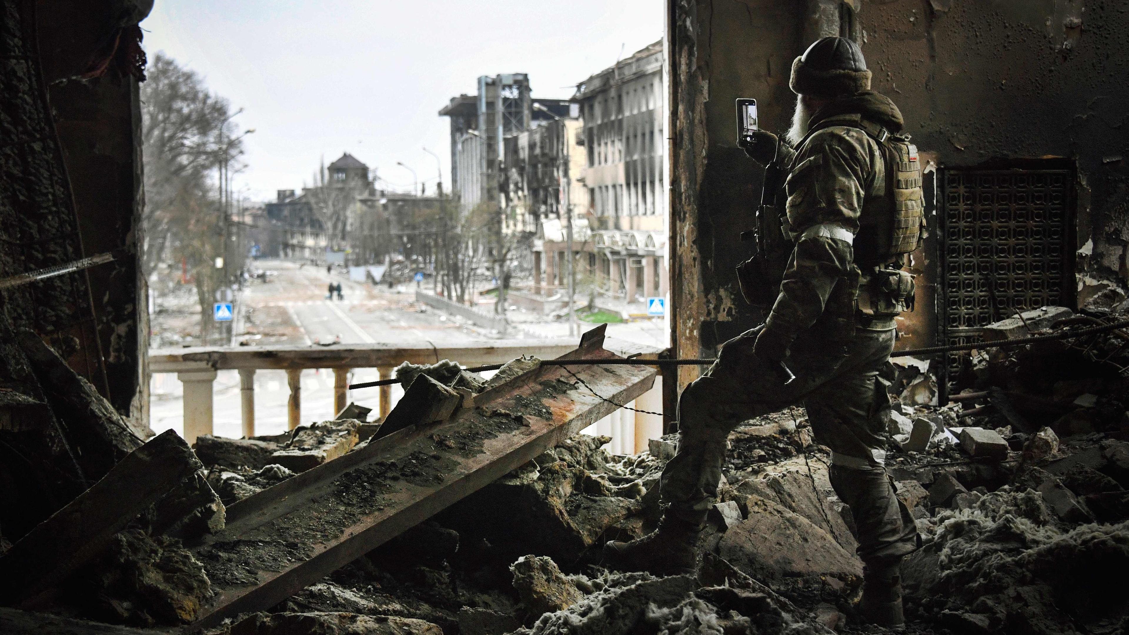 Archiv: Ein russischer Soldat patrouilliert am 12.04.2022 in Mariupol vor dem Theater von Mariupol.