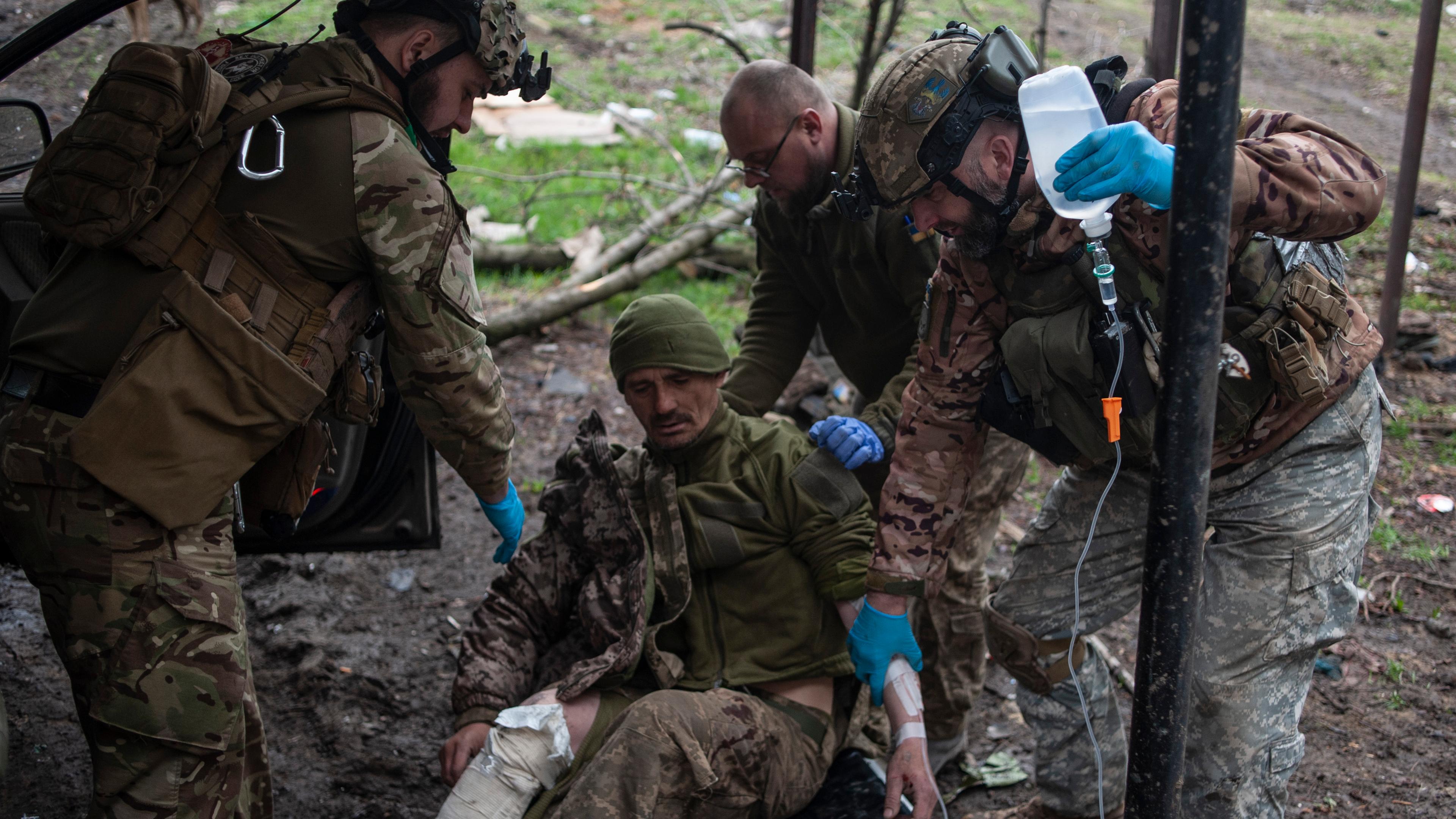 Ukraine, Bachmut: Ukrainische Soldaten leisten einem verwundeten Soldaten erste Hilfe.