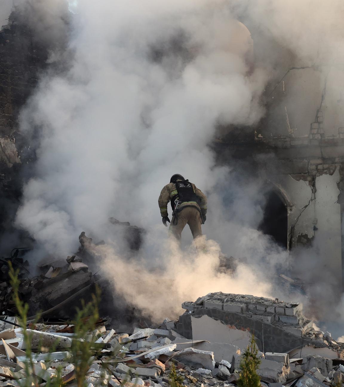Ukraine, Charkow: Ein Feuerwehrmann geht durch den Qualm eines brennenden Hauses, nach russischen Beschuss.