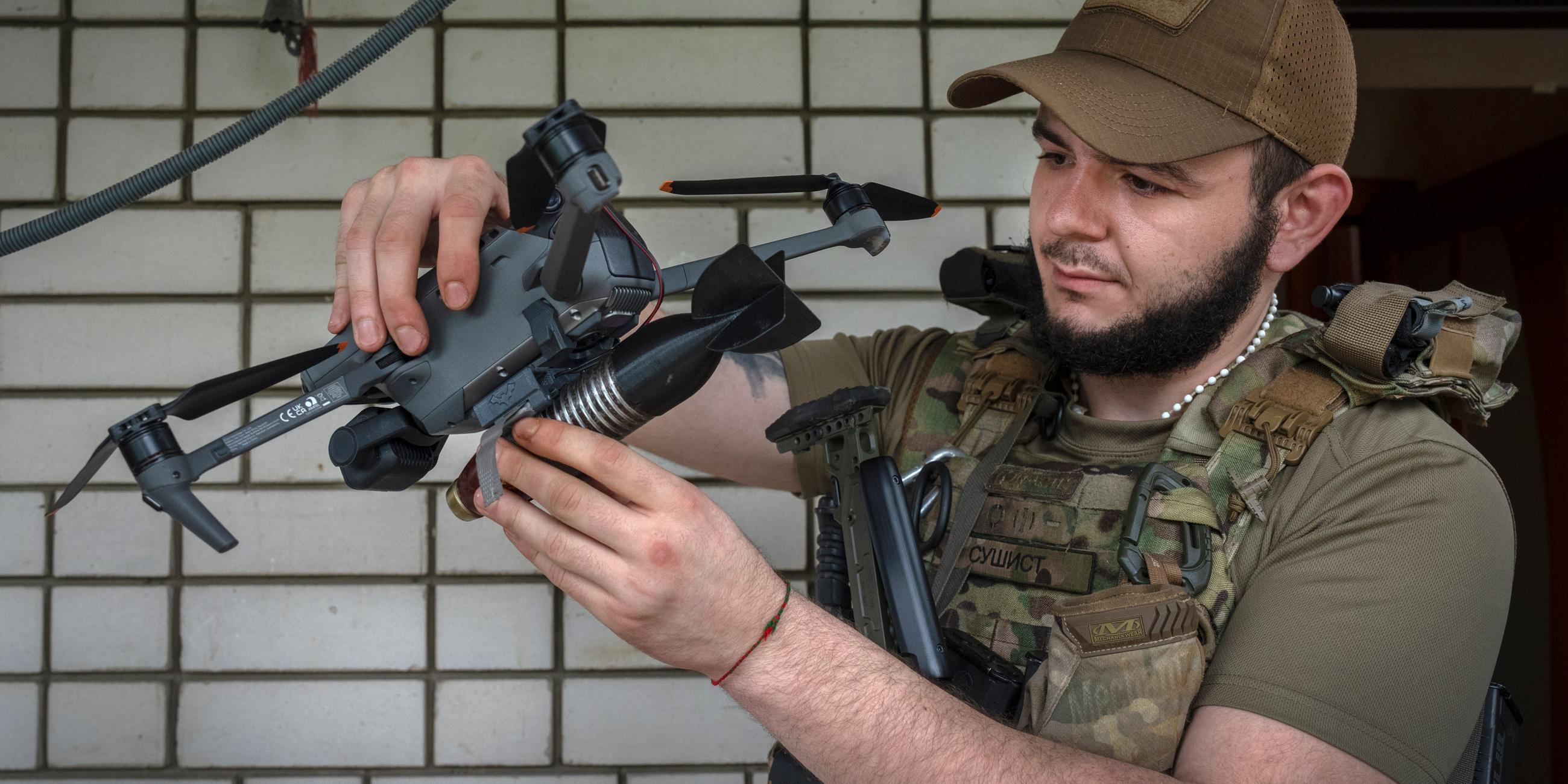 Ukraine, Donezk: Ein Offizier der 59. motorisierten Brigade der Ukraine befestigt eine Bombe auf eine Drohne.