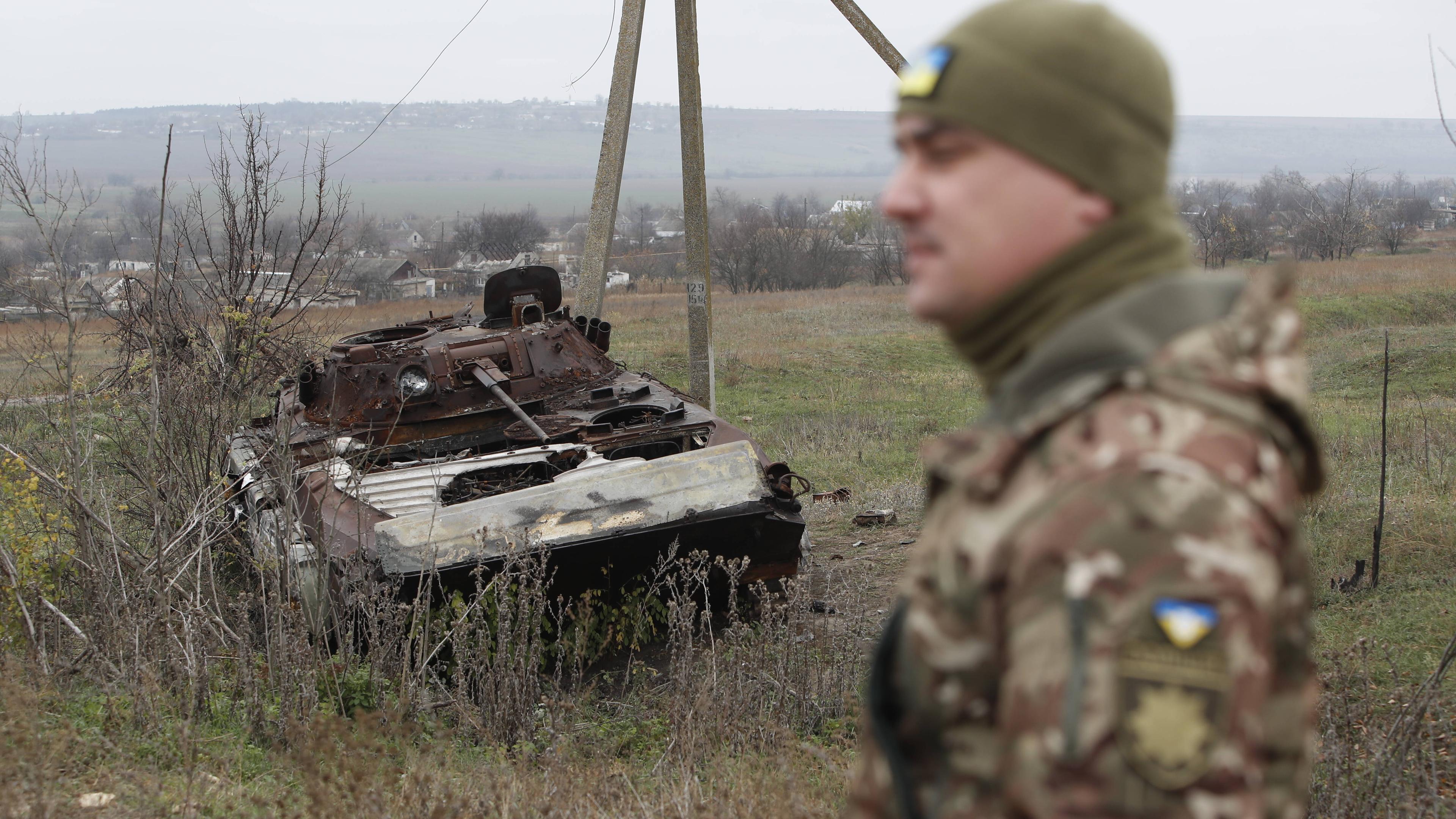 Ukrainischer Soldat vor dem Wrack eines russischen Panzers