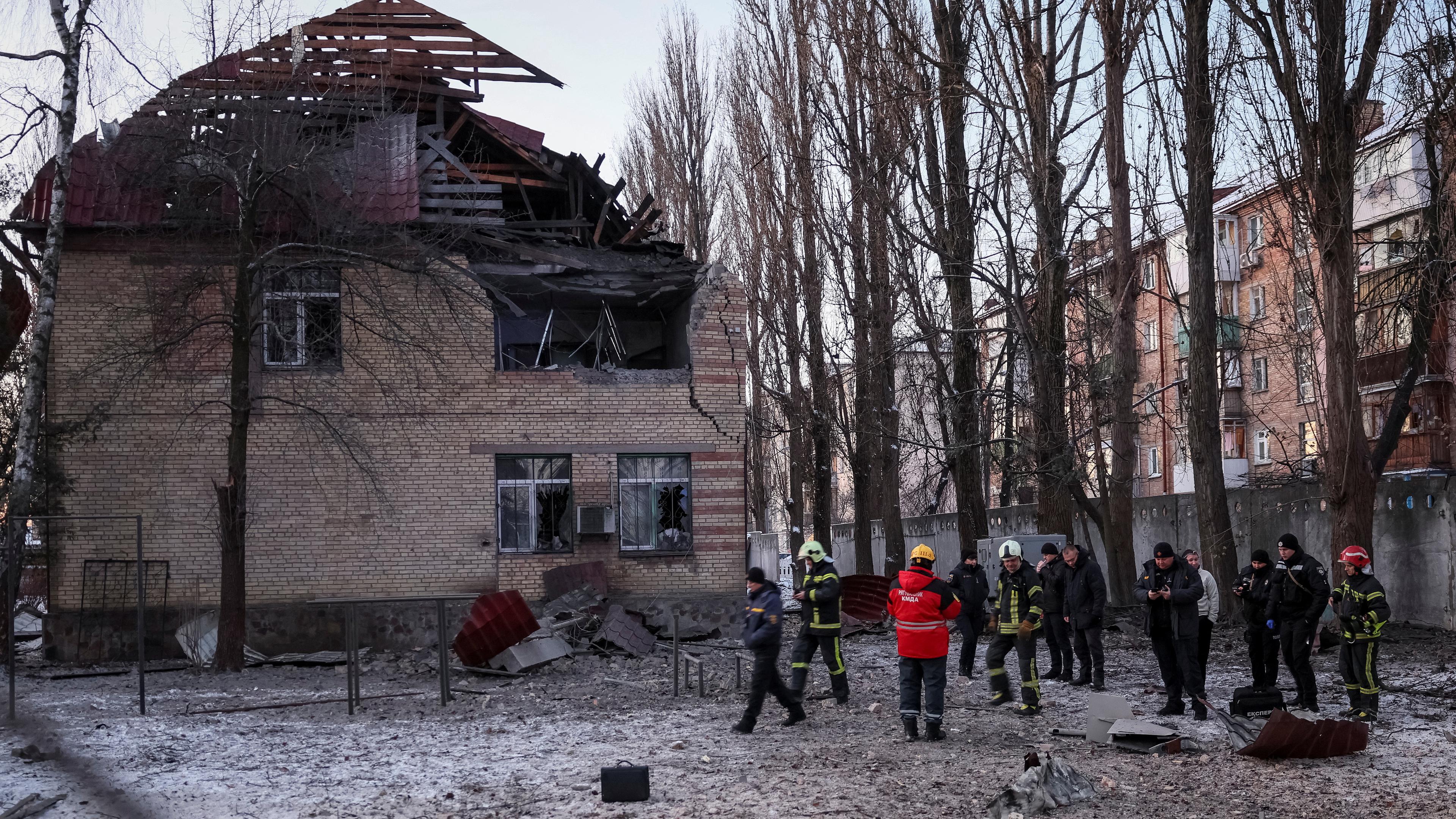 Rettungskräfte und Polizeibeamte untersuchen Teile der Drohne am Ort eines zerstörten Gebäudes in Kiew (Ukrainne), aufgenommen am 14.12.2022
