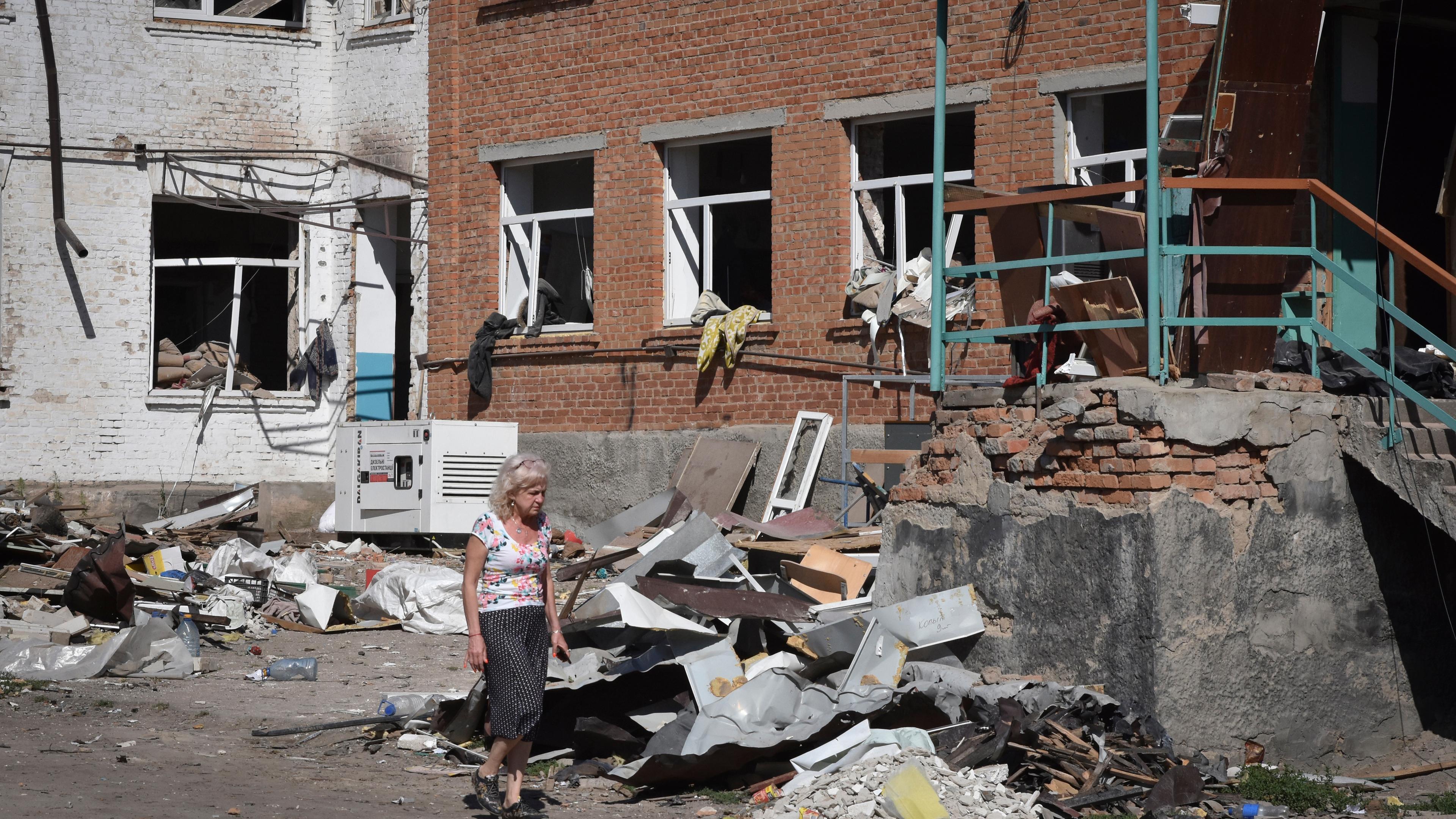 Ukraine, Orichiw: Eine Frau geht neben Gebäuden, die bei dem russischen Angriff am 09.07.23 zerstört wurden.