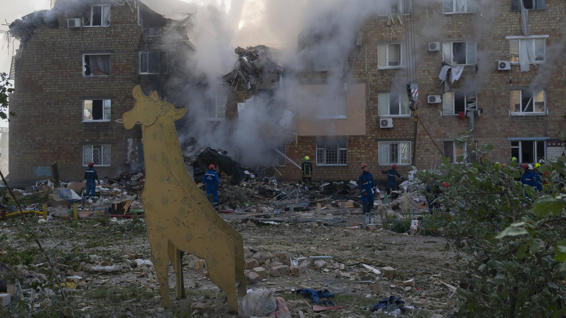 Rettungskräfte suchen unter Trümmern eines Wohnhauses nach Menschen. 