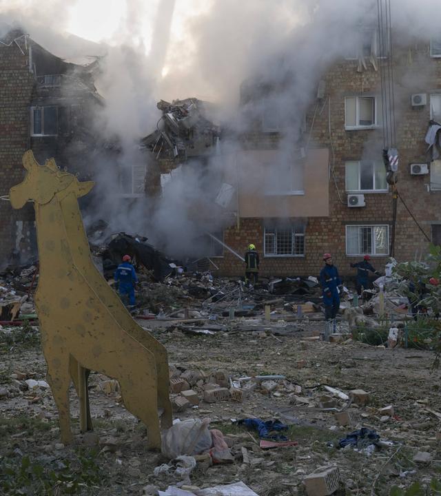 Rettungskräfte suchen unter Trümmern eines Wohnhauses nach Menschen. 