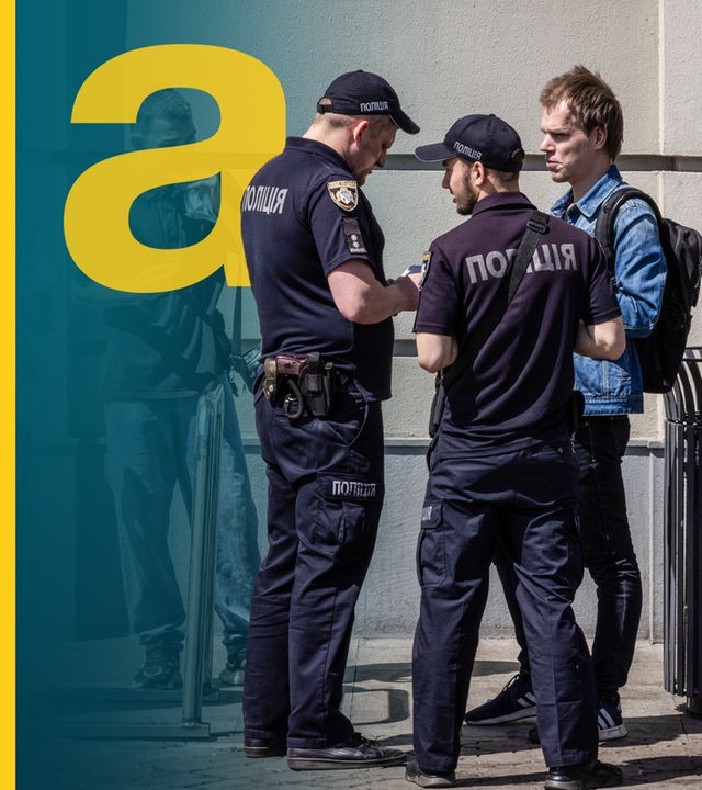 Polizisten kontrollieren die Ausweisdokumente junger Männer in Dnipro