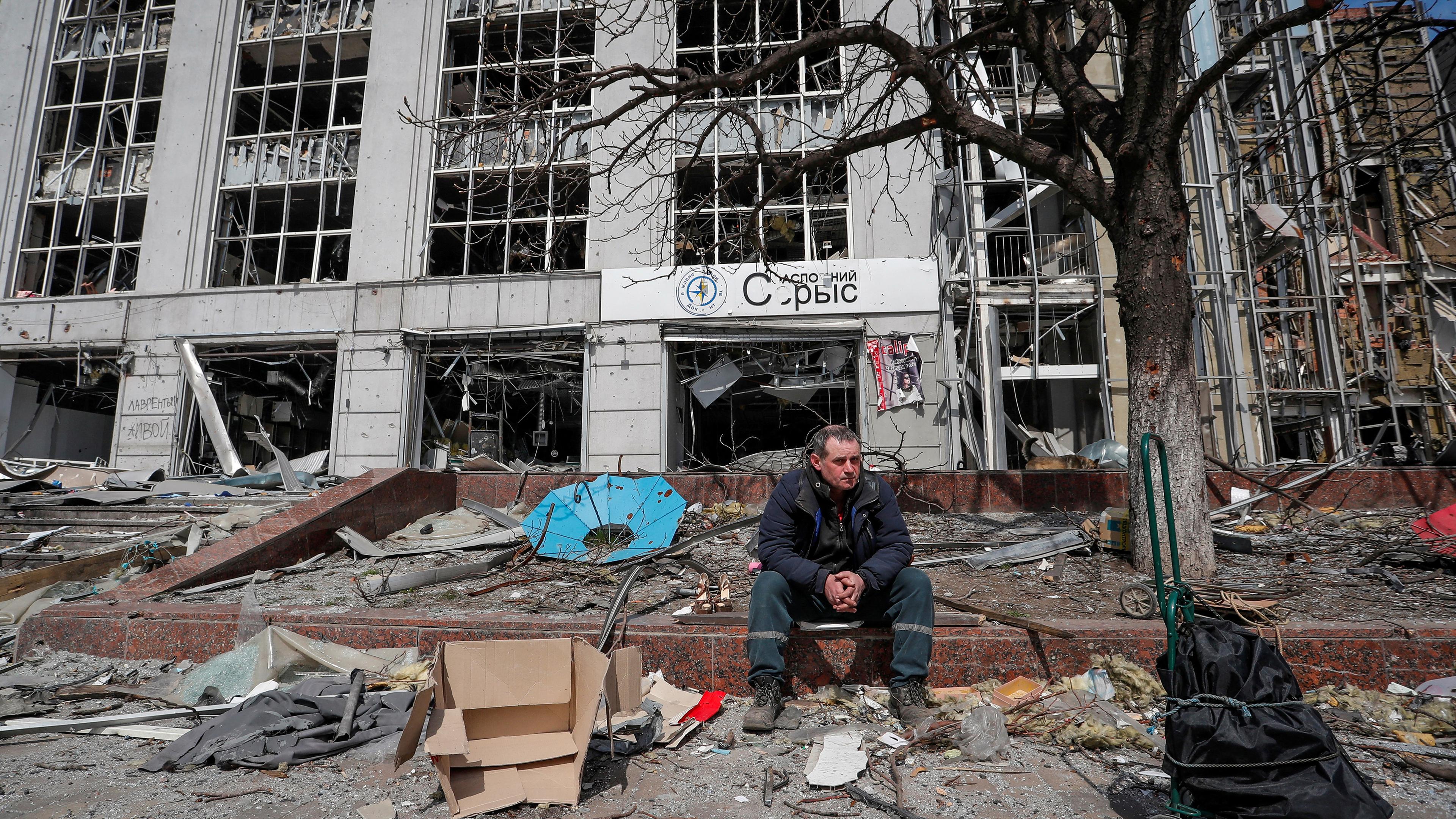 Ein Mann sitzt vor einer Ruine in der Stadt Mariupol.