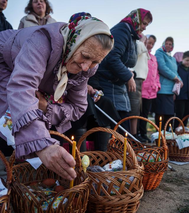 Eine ältere Frau bereitet ihre Osterkörbe für die Segnung während des orthodoxen Osterfestes im Dorf Krasne, Ukraine vor.