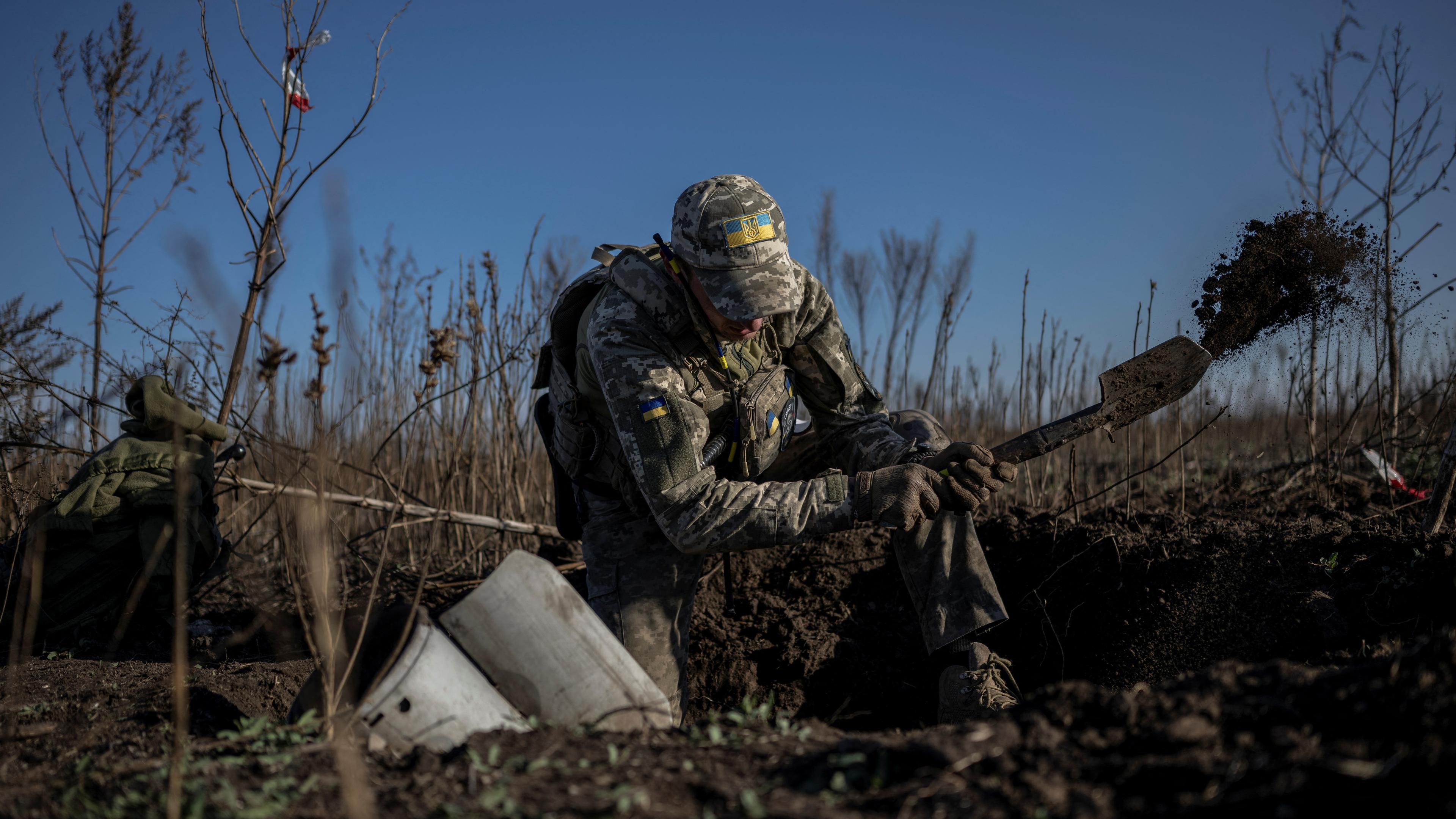 Ein ukrainischer Soldat gräbt einen Blindgänger aus.