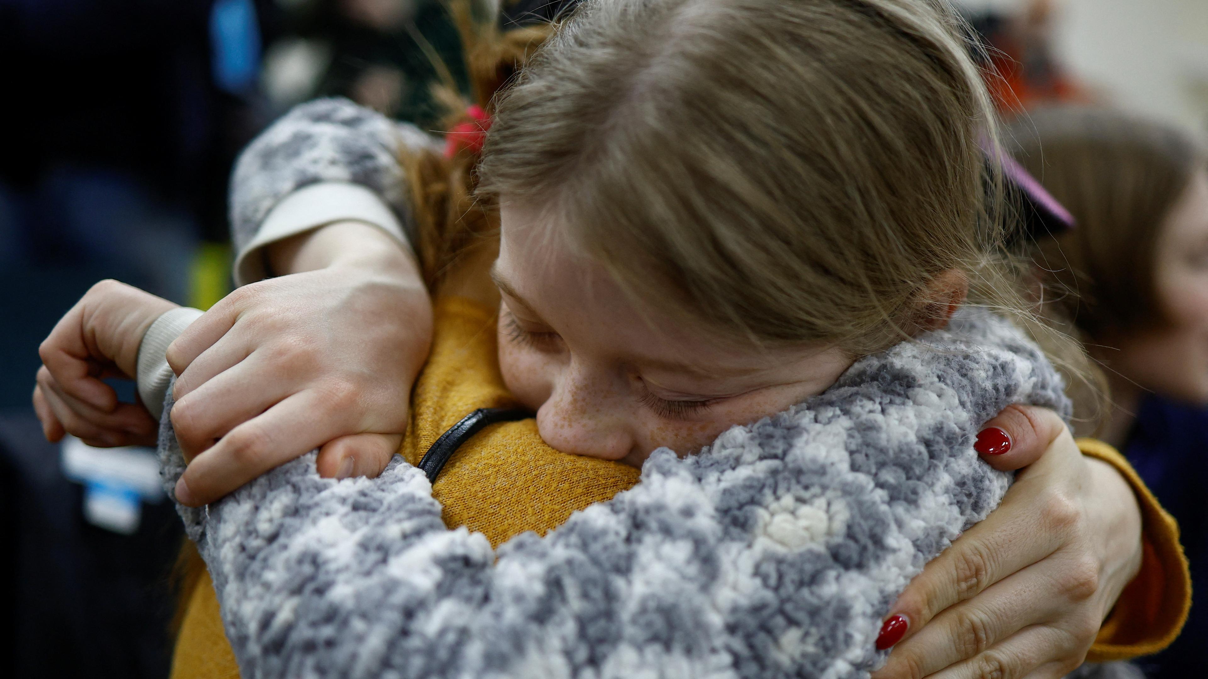 Eine Mutter umarmt ihre Tochter, die zuvor nach Russland verschleppt worden war.