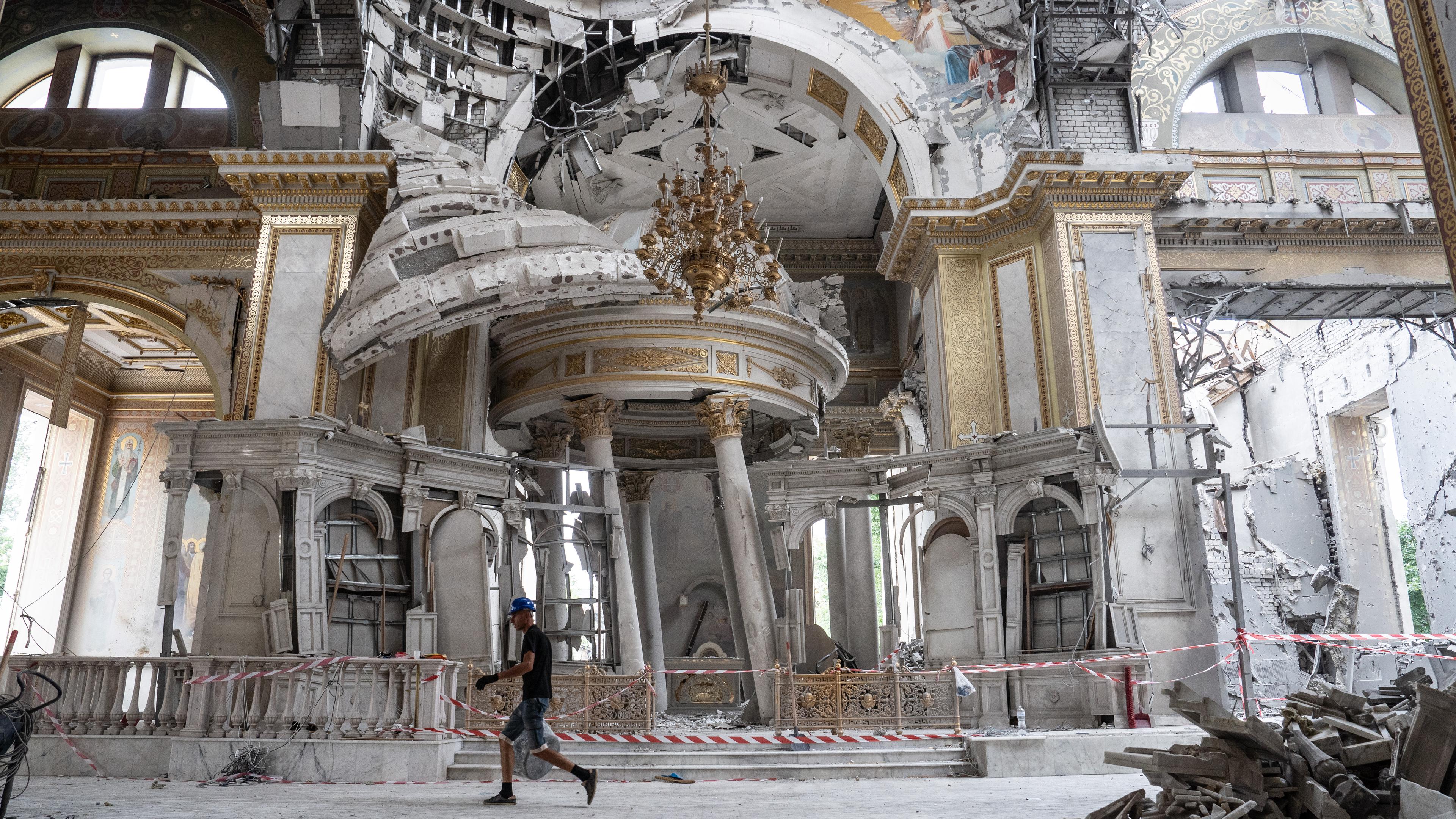 Ein Mann geht durch eine zerstörte Kathedrale.