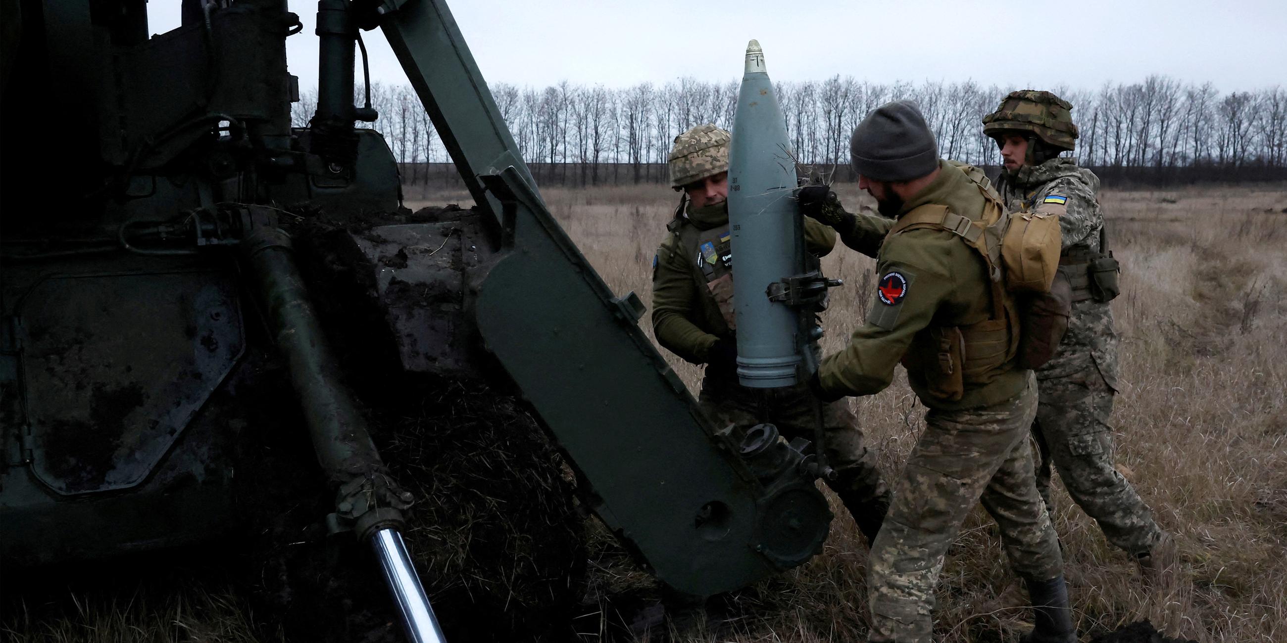 Ukrainische Soldaten laden ein Projektil zum Abfeuern aus einer Kanone.
