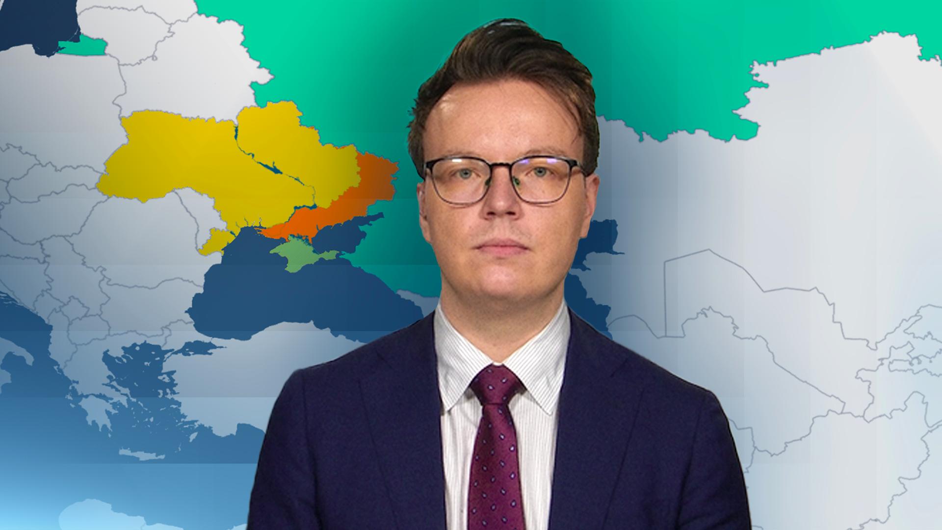 Militärexperte Fabian Hoffmann. Im Hintergund ist eine Landkarte, auf der die Ukraine und Russland farbig markiert sind.