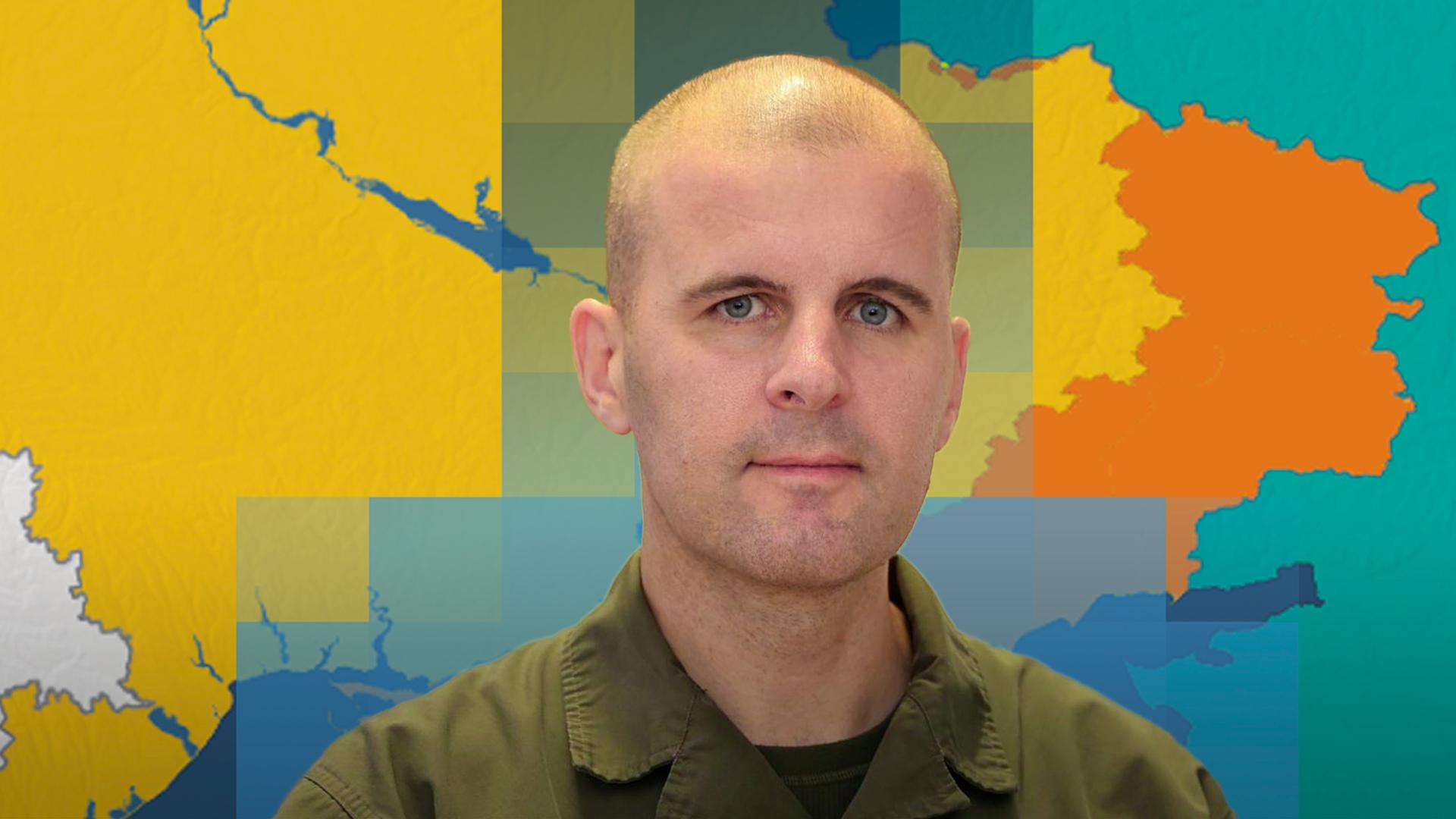 Oberst Markus Reisner ist vor einer Karte der Ukraine mit dem aktuellen Frontverlauf abgebildet.