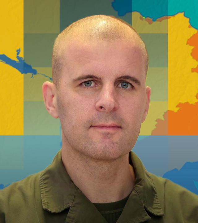 Oberst Markus Reisner ist vor einer Karte der Ukraine mit dem aktuellen Frontverlauf abgebildet.