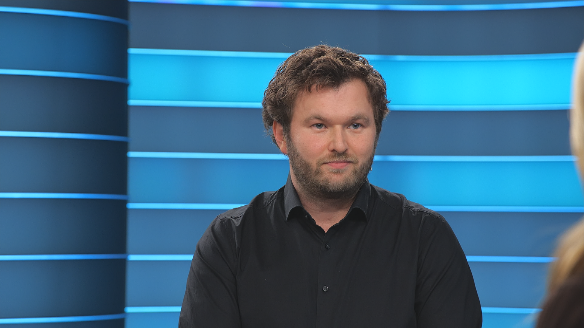 ZDF-Reporter für Russland Sebastian Ehm im ZDFheute live Studio. Er trägt ein schwarzes Hemd.