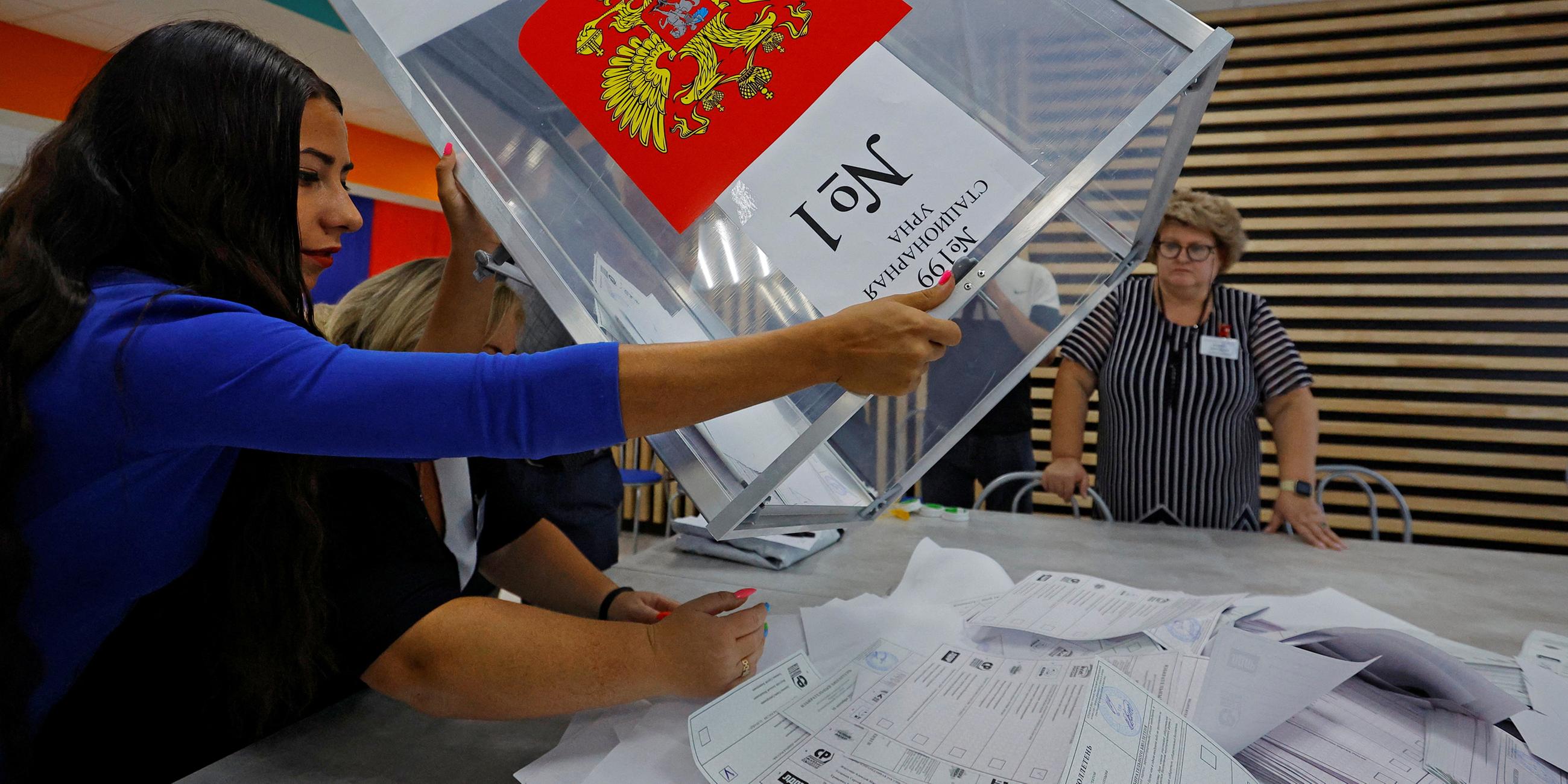 Mitglieder einer Wahlkommission leeren eine Wahlurne, um die Stimmzettel auszuzählen