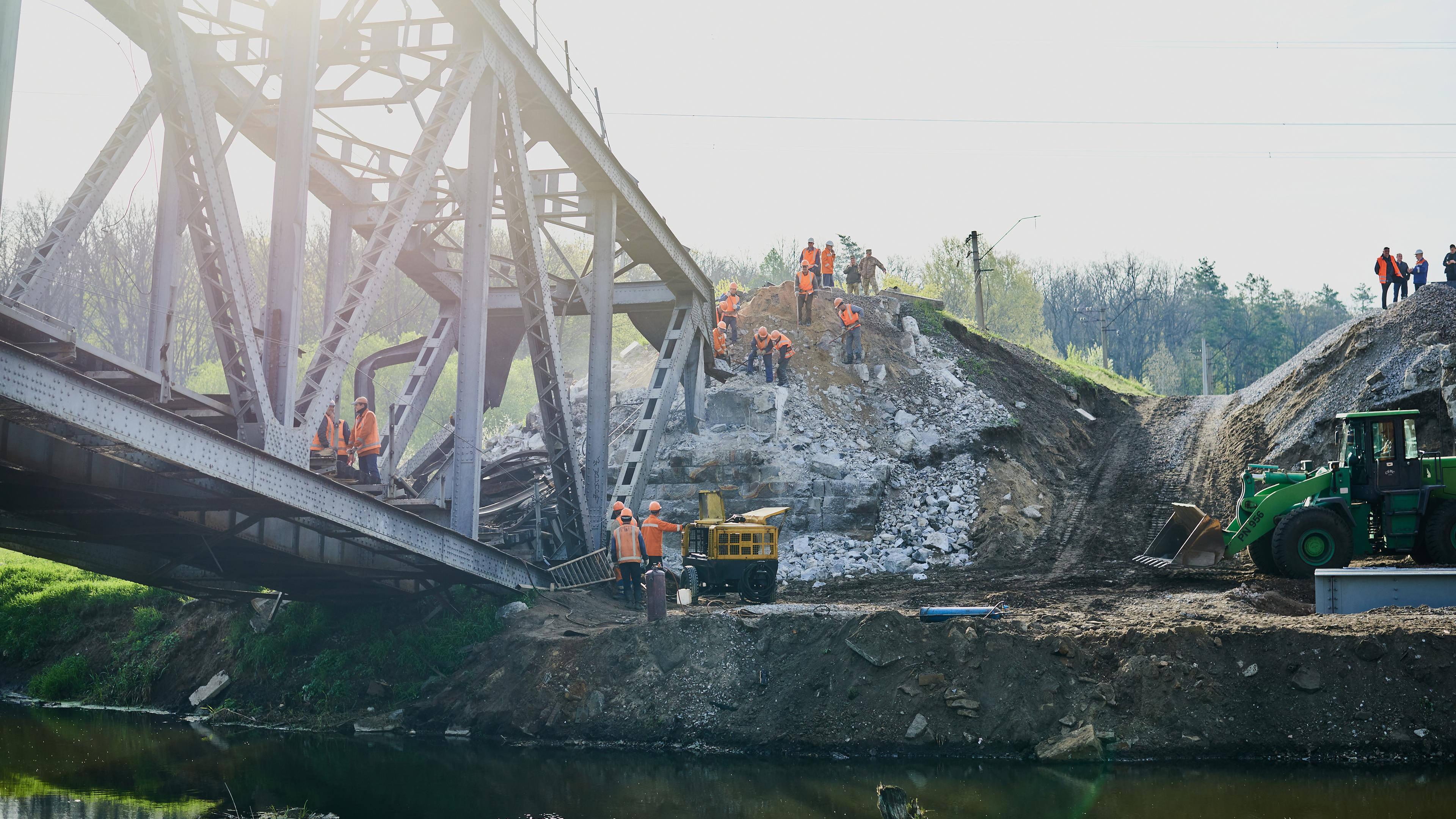 Ukrainische Arbeiter reparieren eine zerstörte Bahnbrücke bei Irpin