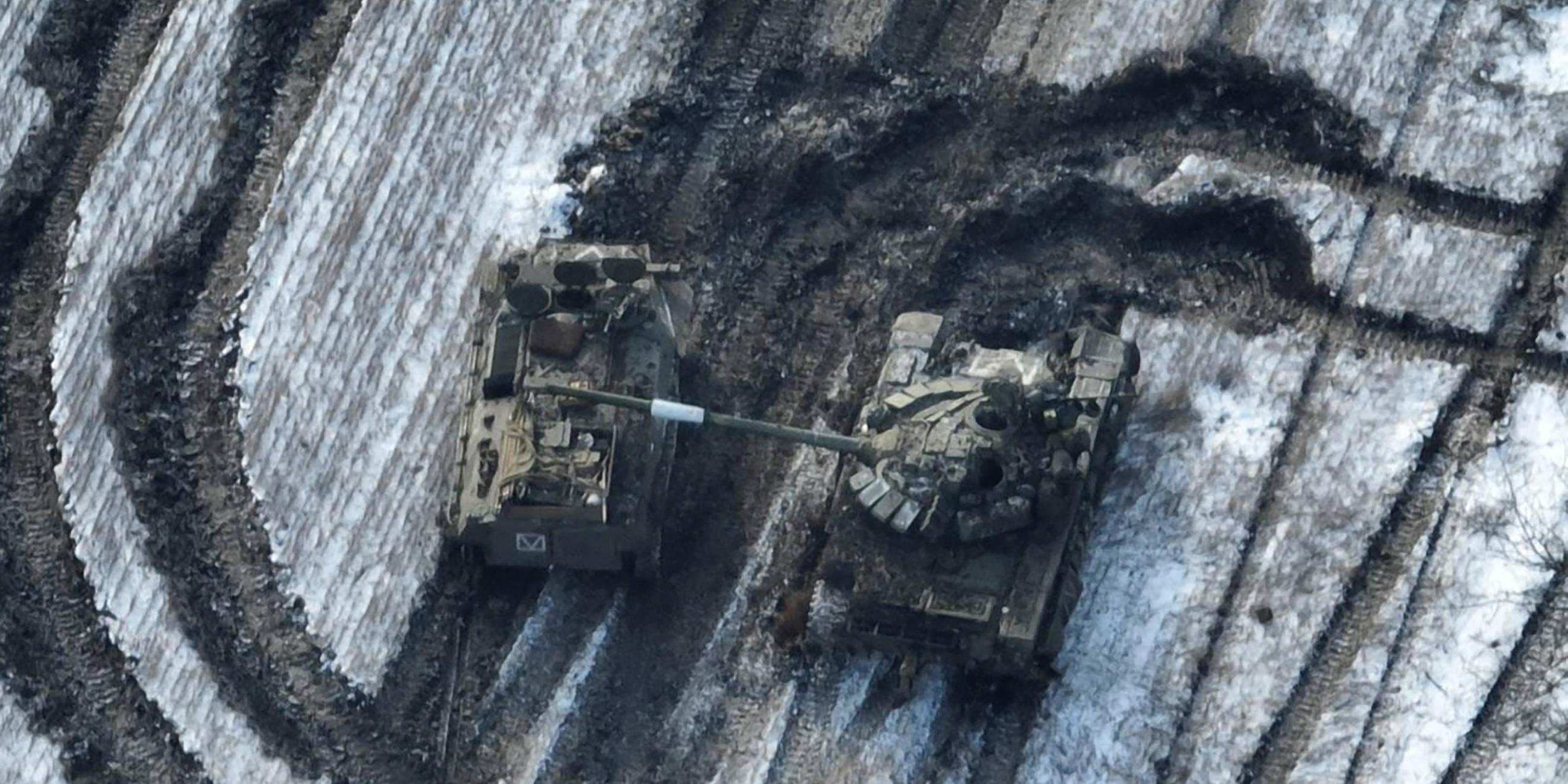 Zwei beschädigte Militärfahrzeuge stehen auf einem schneebedecktend Feld