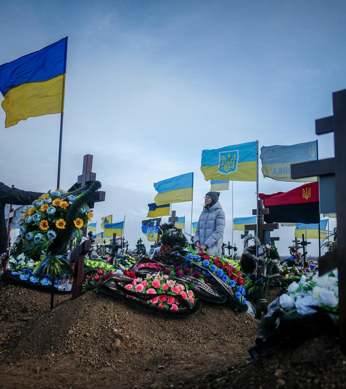 Ukraine, Odessa: Anna, die Ehefrau eines vor zwei Monaten getöteten Soldaten, und der Vater Oleksandr stellen auf dem Friedhof der Hafenstadt Odessa die Ukrainische Nationalflagge am Grab ihres Ehemannes auf.