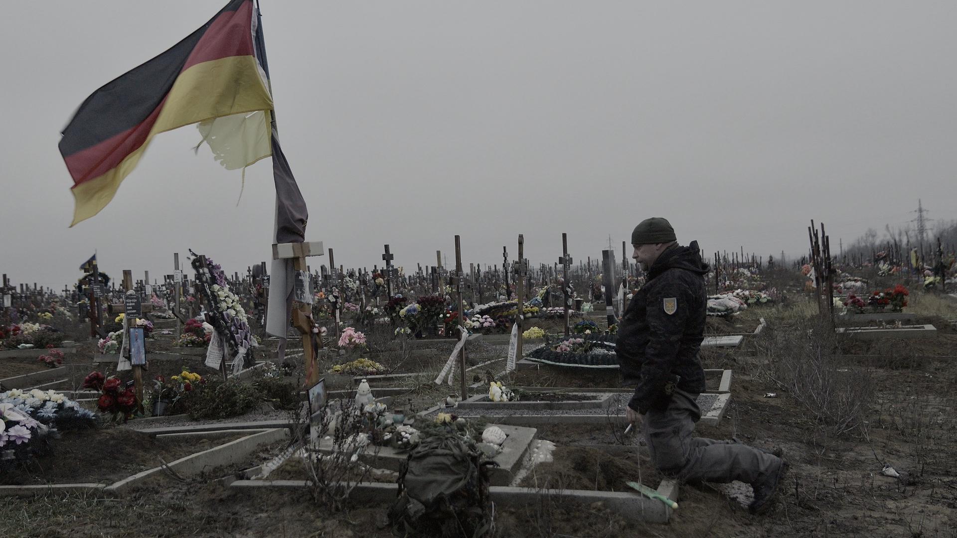 Bruder kniet am Grab von Michael P. in der Ukraine