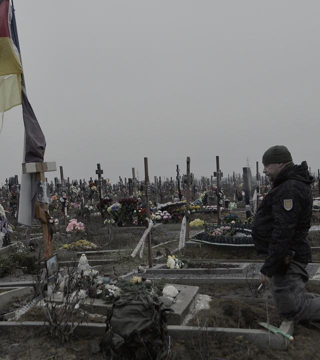 Bruder kniet am Grab von Michael P. in der Ukraine