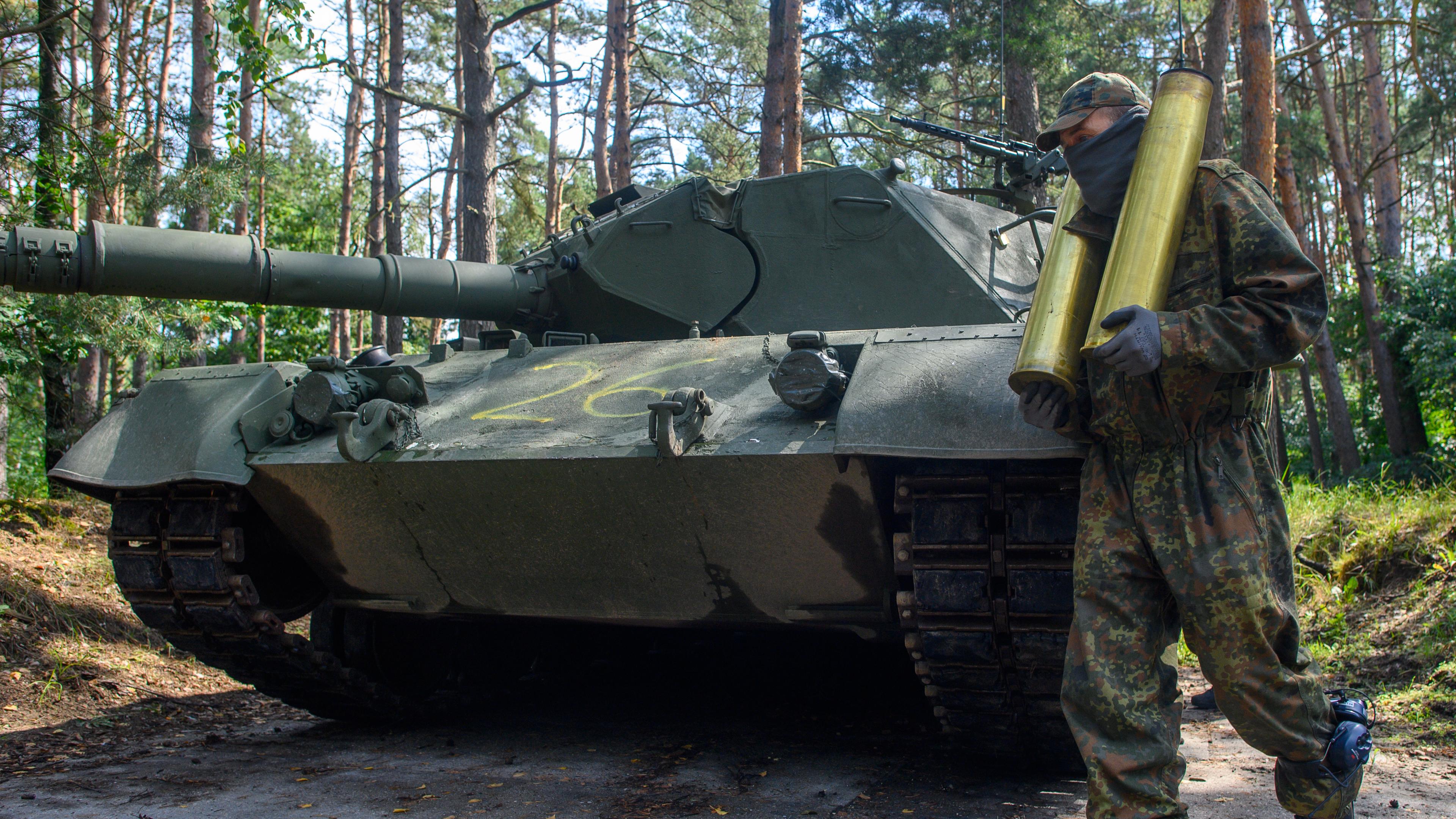 Ein vermummter ukrainischer Soldat entlädt auf dem Truppenübungsplatz Klietz die Hülsen verschossener Panzermunition von einem Kampfpanzer vom Typ "Leopard 1 A5".