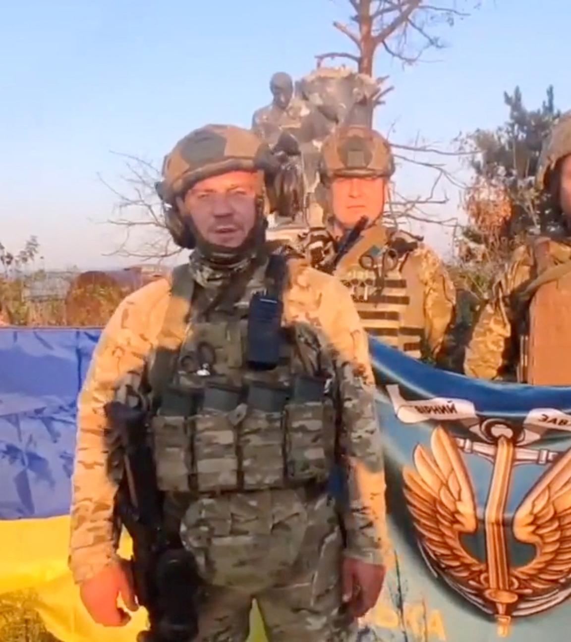 Ukrainische Soldaten stehen mit ukrainischer Flagge in Uroschajne