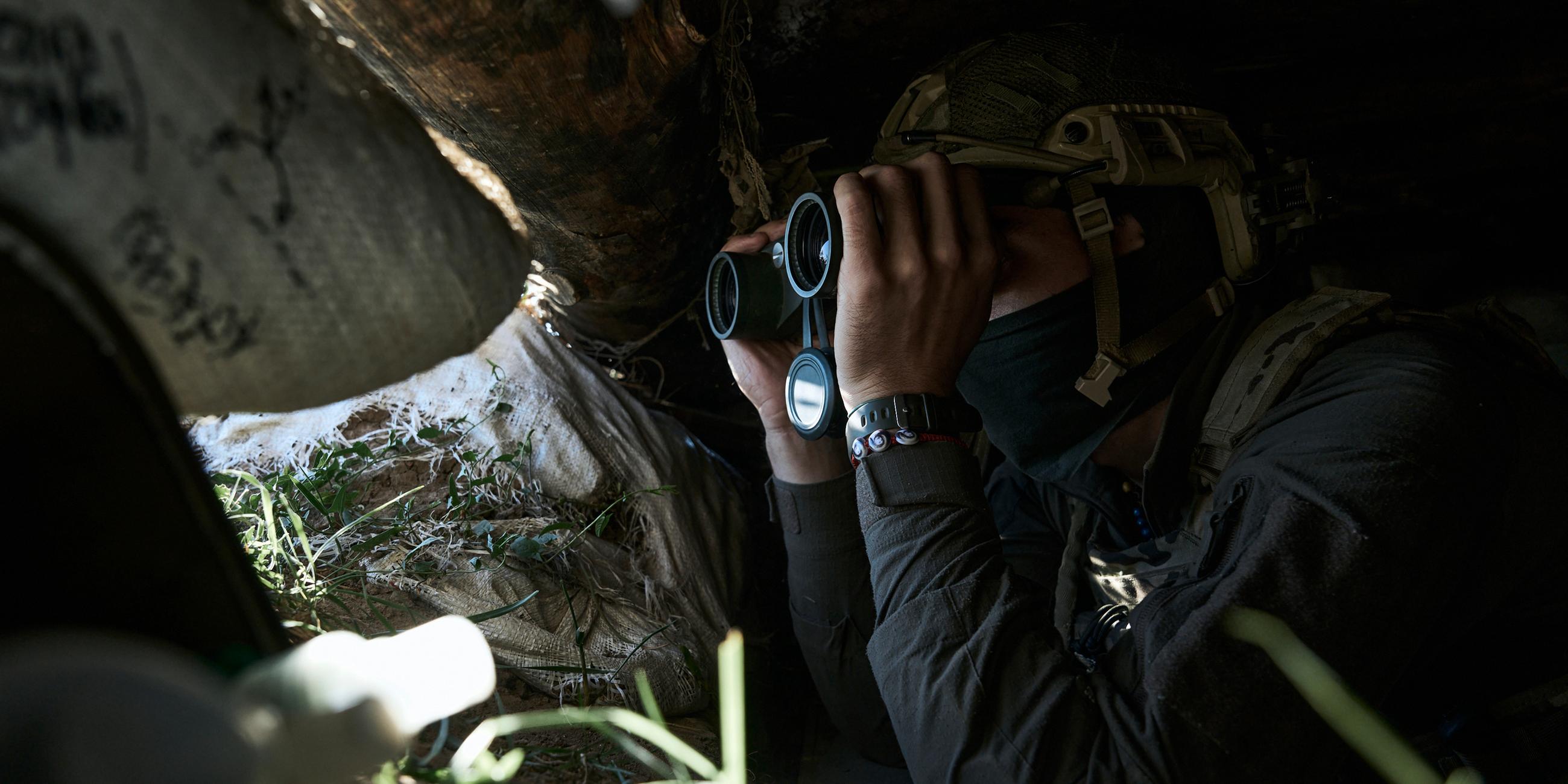 Ein ukrainischer Soldat blickt durch ein Fernglas aus dem Bunker an der Frontlinie in der Nähe von Bachmut, Gebiet Donezk, Ukraine