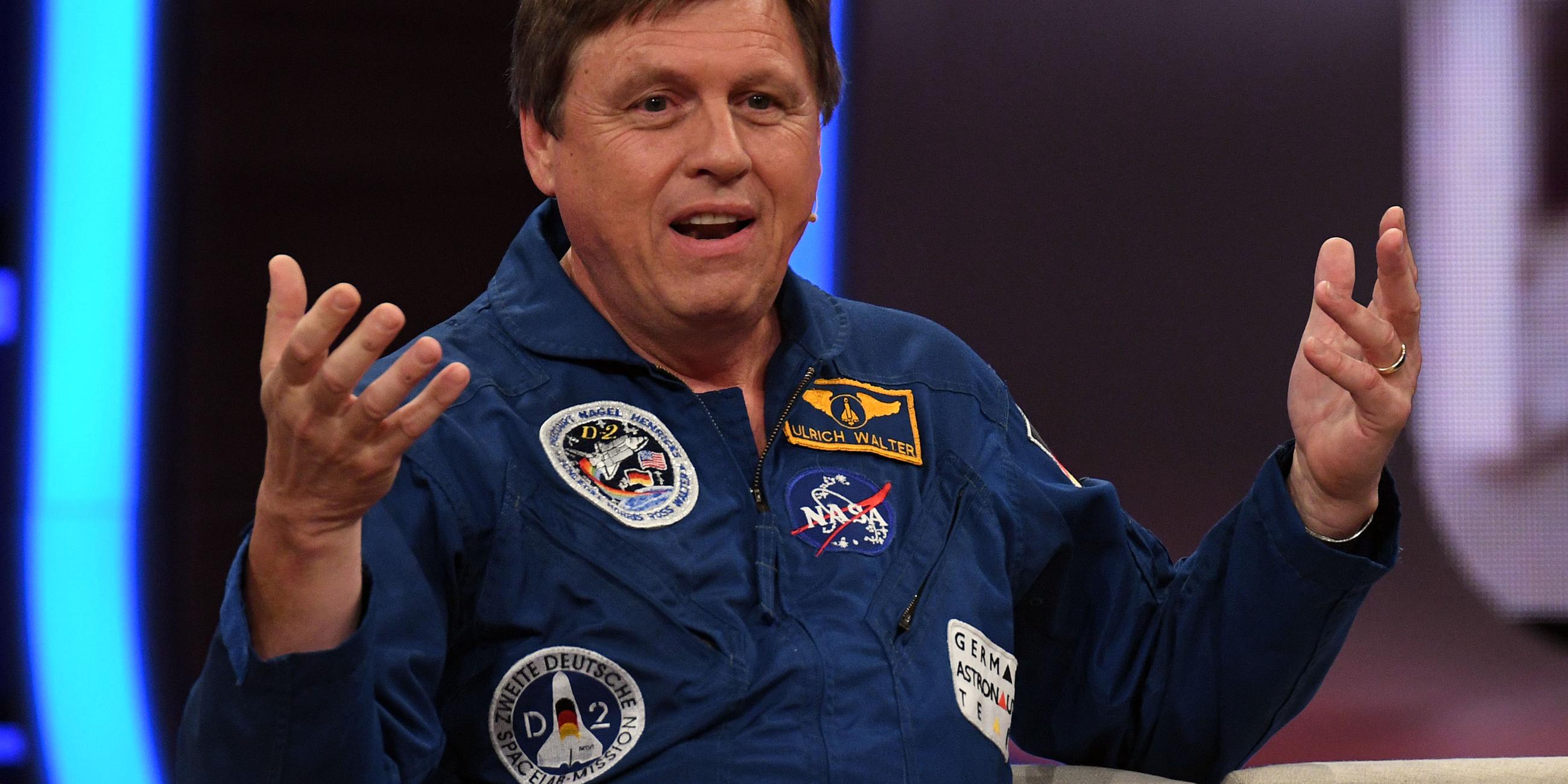 Der Astronaut Ulrich Waltersitzt auf einer Couch, gestikuliert und spricht.
