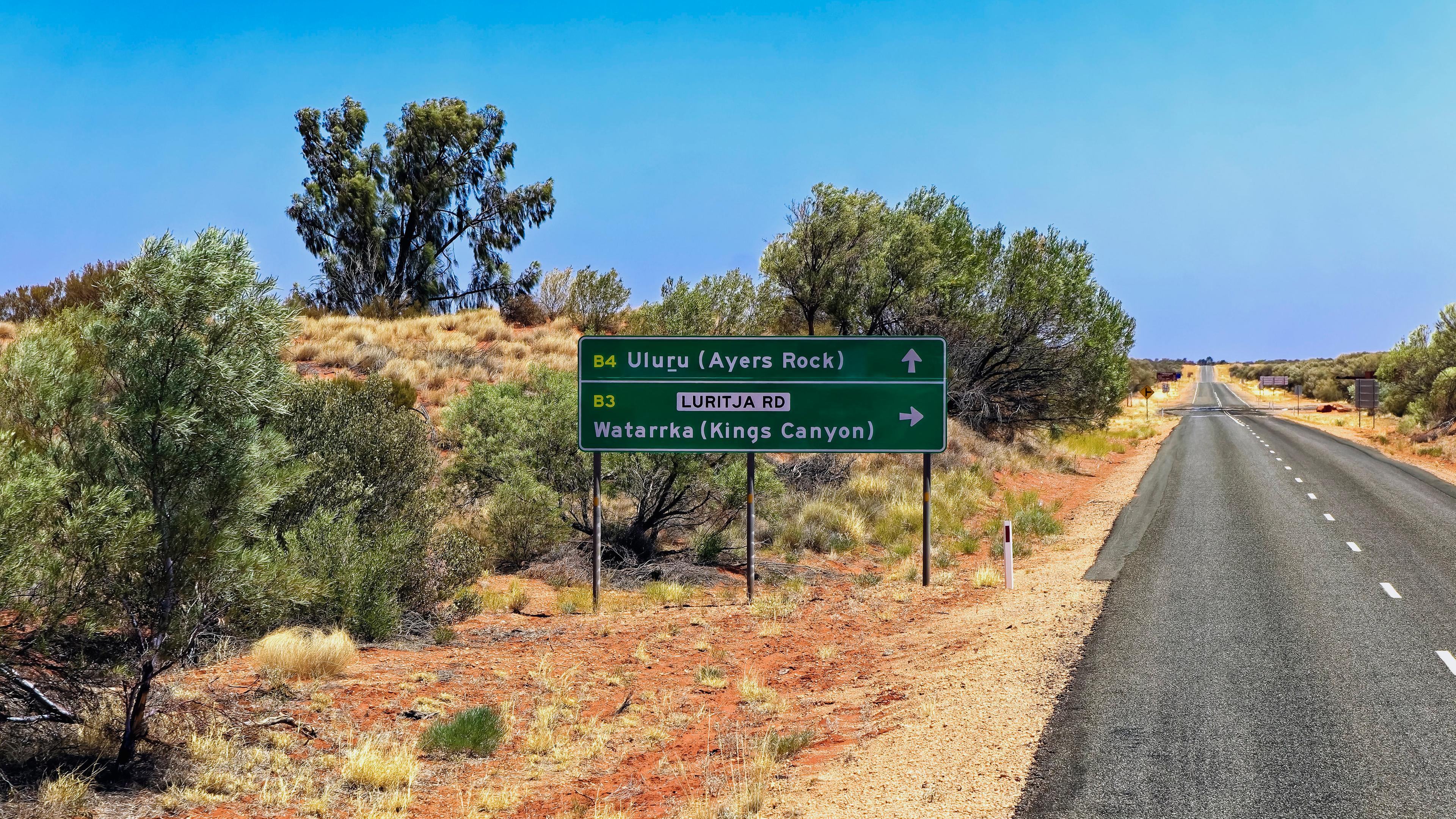 Ein Schild auf dem Lasseter Highway im australischen Outback zeigt die Richtung "Uluru/Ayers Rock".