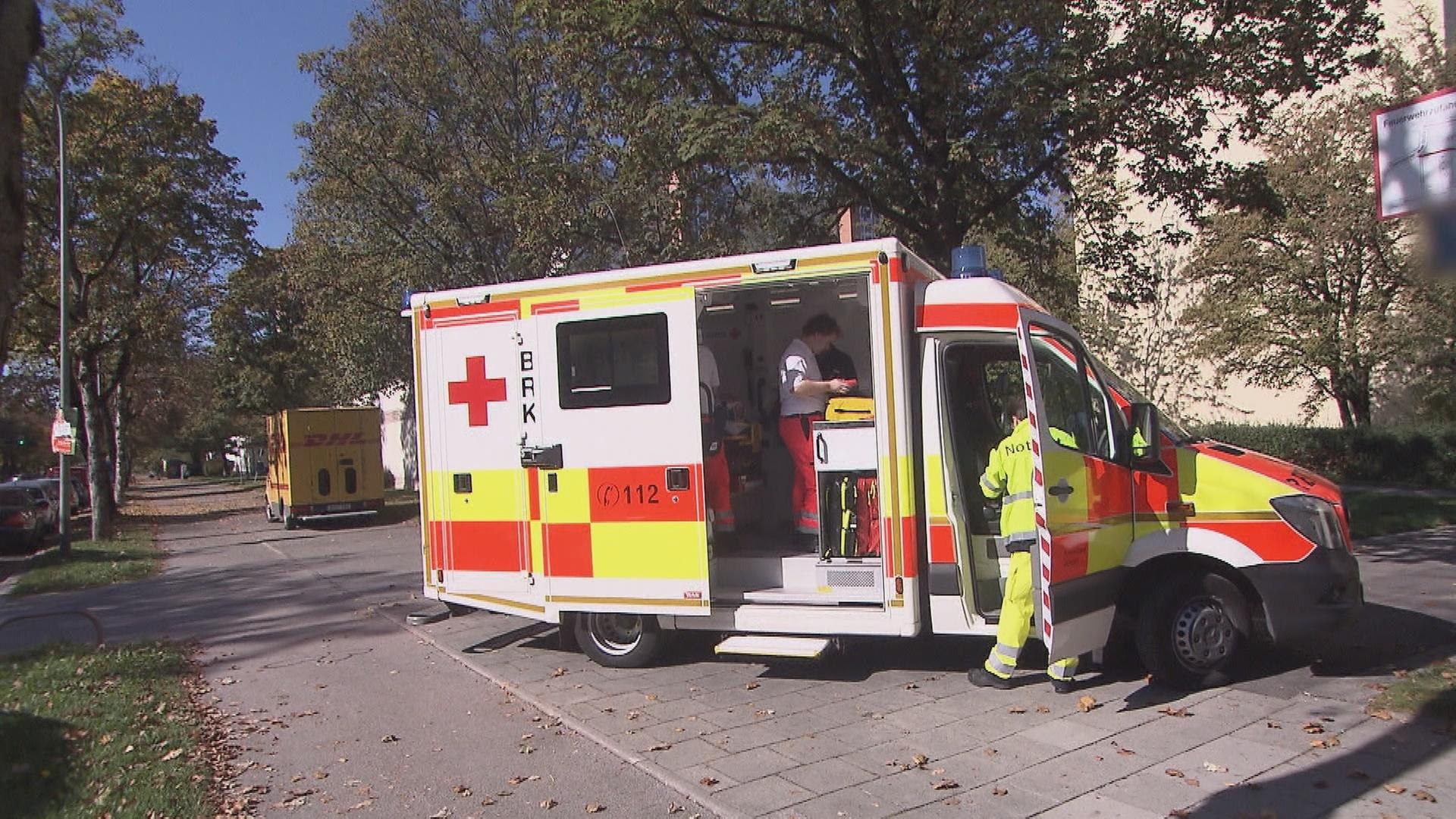 "Um Leben und Tod - Dauereinsatz für den Notarzt": Ein Rettungswagen steht auf einem Weg, die Türen sind geöffnet. Der Notarzt und die Sanitäter sind am und im Wagen beschäftigt.