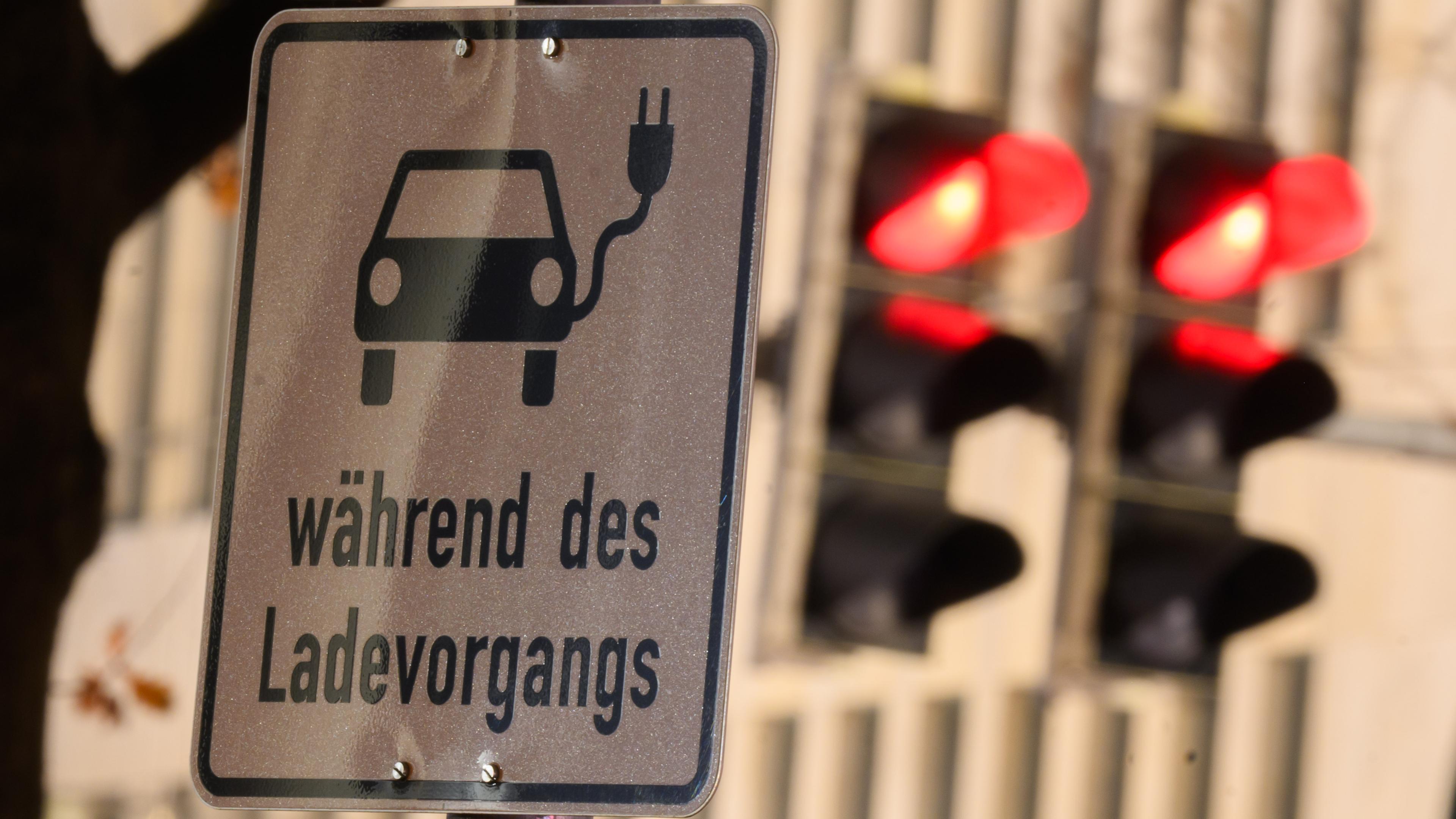 19.12.2023, Niedersachsen, Hannover: Ein Schild mit einem Symbol für ein Elektroauto und den Schriftzug ·während des Ladevorgangs· markiert einen Parkplatz an einer Ladesäule.
