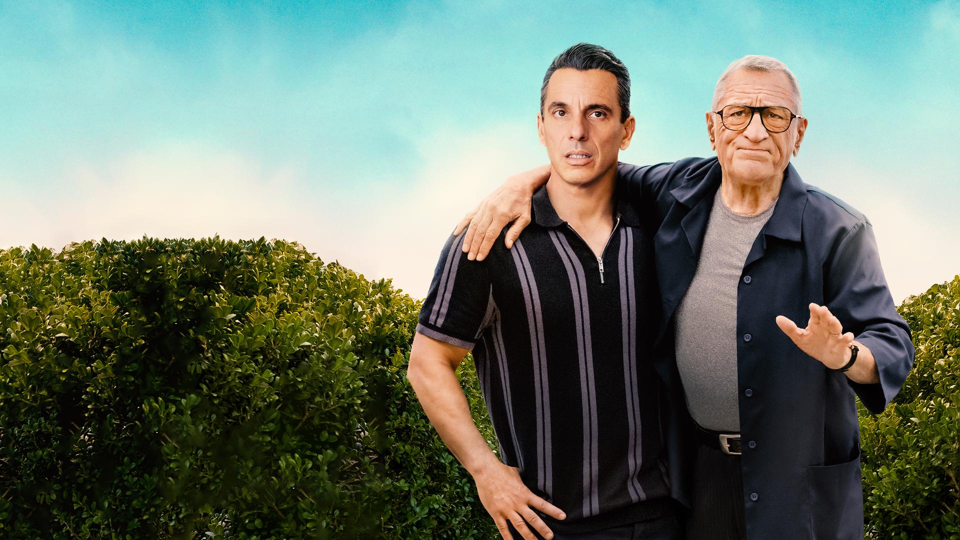 "Und dann kam Dad": Sebastian (Sebastian Maniscalco) und sein Vater Salvo (Robert De Niro) stehen nebeneinander vor einer Hecke und blicken skeptisch nach vorne. Salvo hat einen Arm um seinen Sohn gelegt und macht eine abweisende Geste.