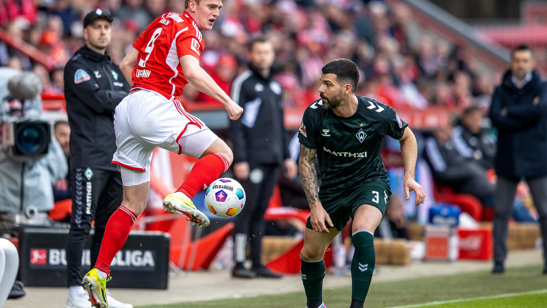  Berlins Mikkel Kaufmann (l) springt zum Ball gegen Anthony Jung von Werder Bremen.