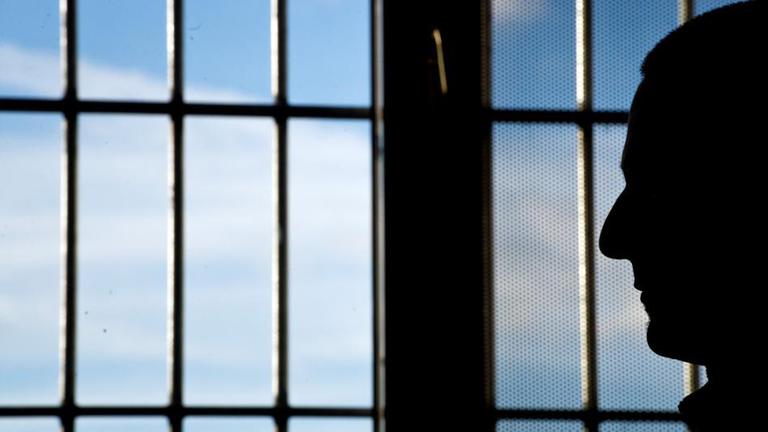Unschuldig hinter Gittern Weggesperrt und abgehakt ein gefaengnisinsasse sitzt vor einem vergitterten fenster
