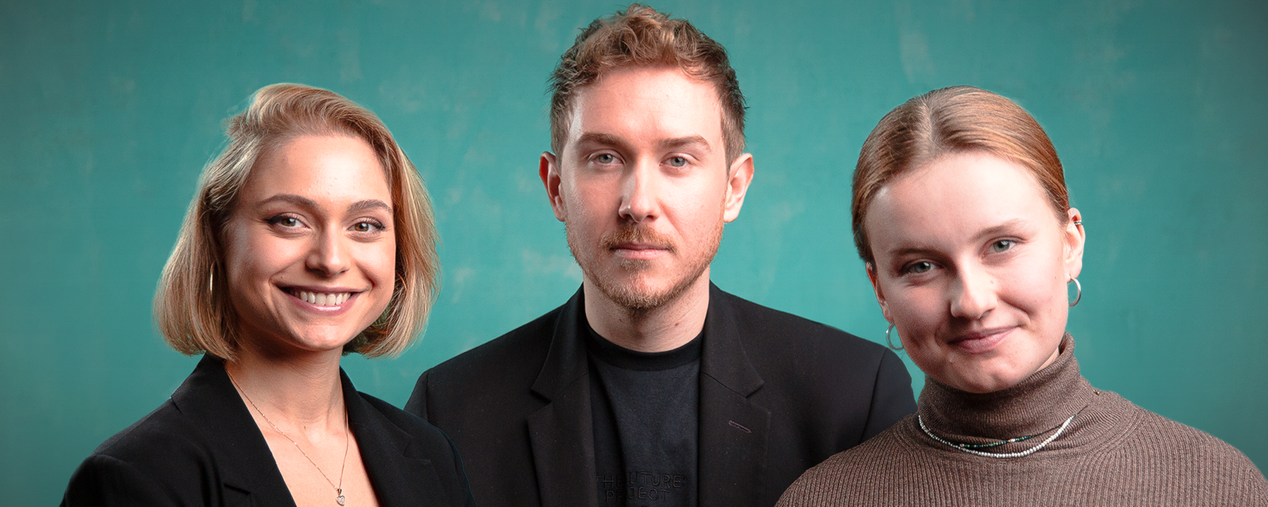 Drei Menschen stehen nebeneinander und schauen in die Kamera: Links eine blonde, lächelnde Frau, in der Mitte ein Mann, rechts eine blonde lächelnde Frau. Der Hintergrund ist grün.