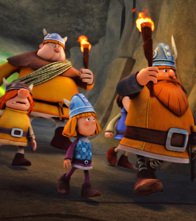 Wickie, Snorre, Faxe und Halvar laufen mit Fackeln durch eine Höhle.