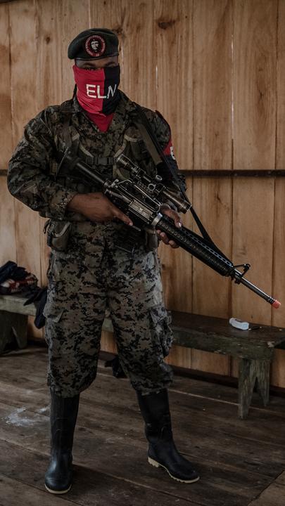 "Unter Gangstern: Gangs in El Salvador": ELN-Kommandant Yerson steht vermummt in einer Hütte und trägt ein Gewehr.